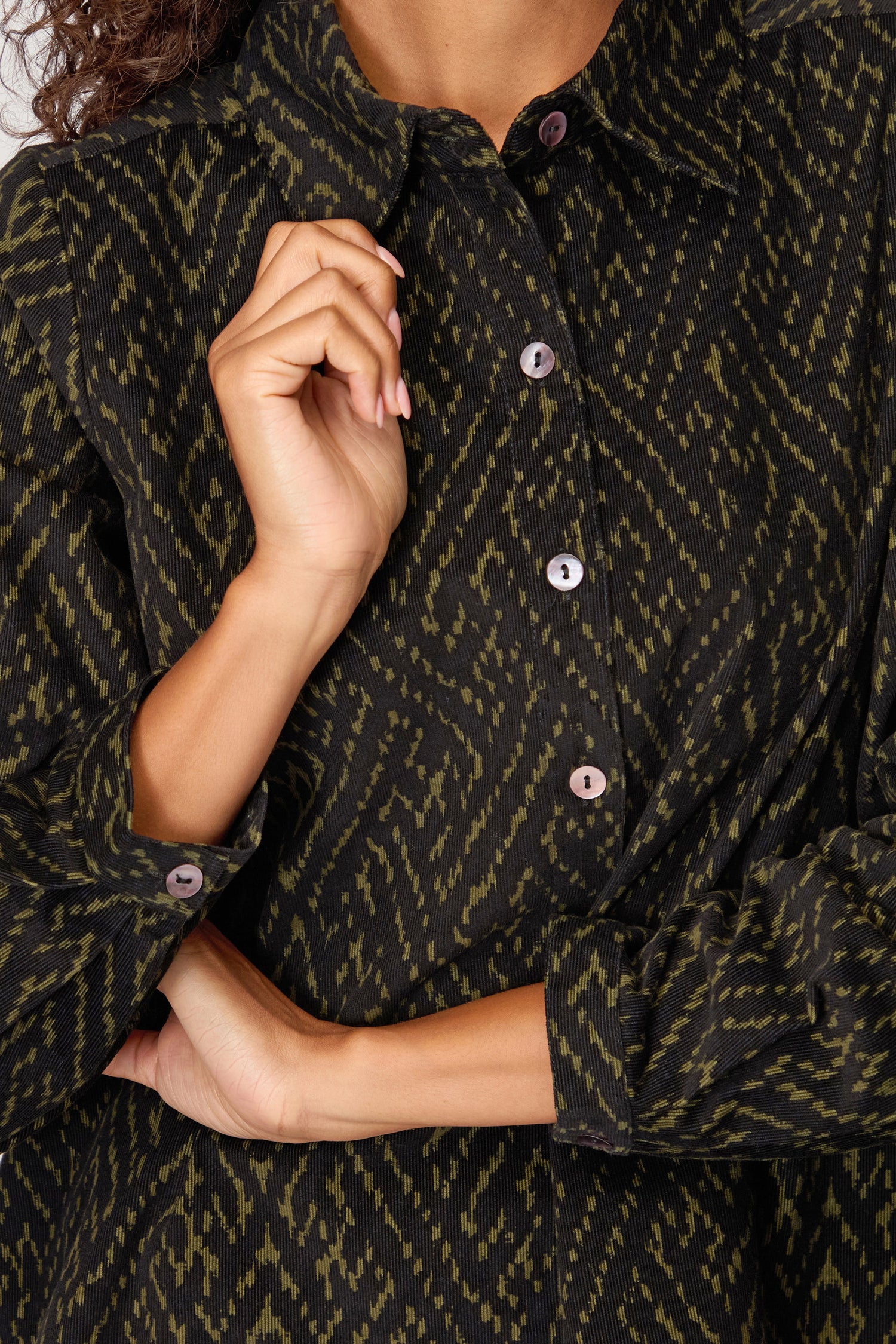 A person wearing the Ornate Textured Cord Black and Khaki Shirt with a relaxed fit, one hand near their collar and the other arm crossed—ideal for elevating your autumn wardrobe.