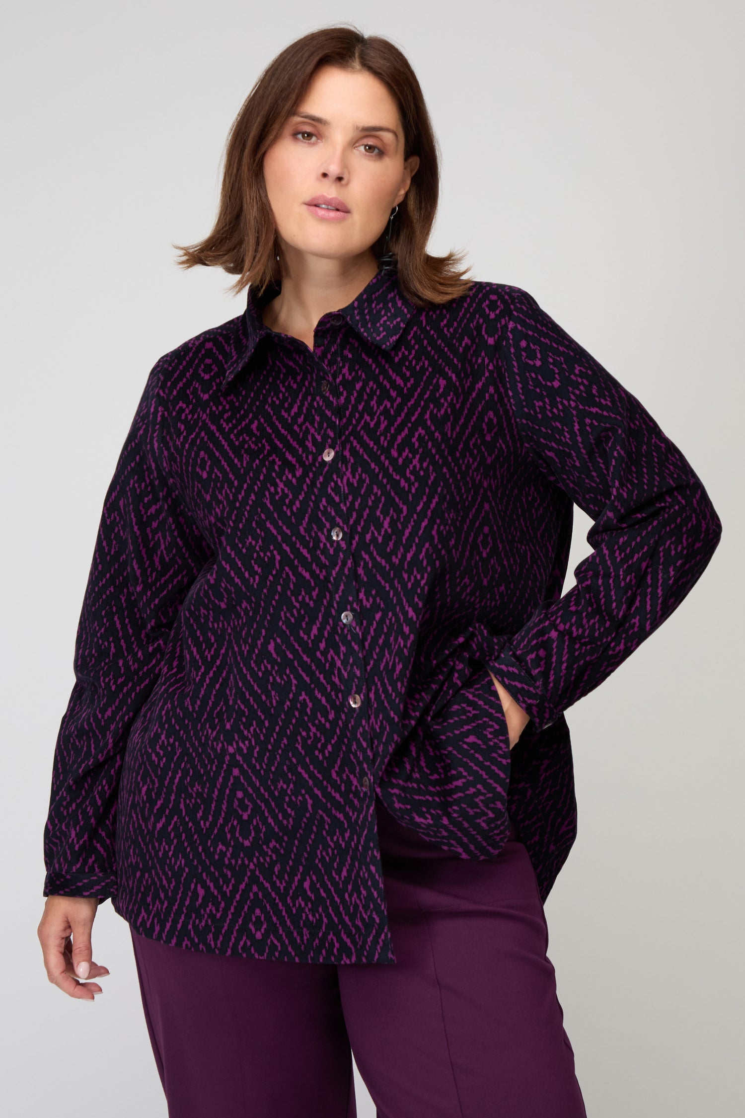 Wearing the Ornate Textured Night and Plum Cord Shirt with a relaxed fit, a woman stands with one hand in her pocket against a plain background.