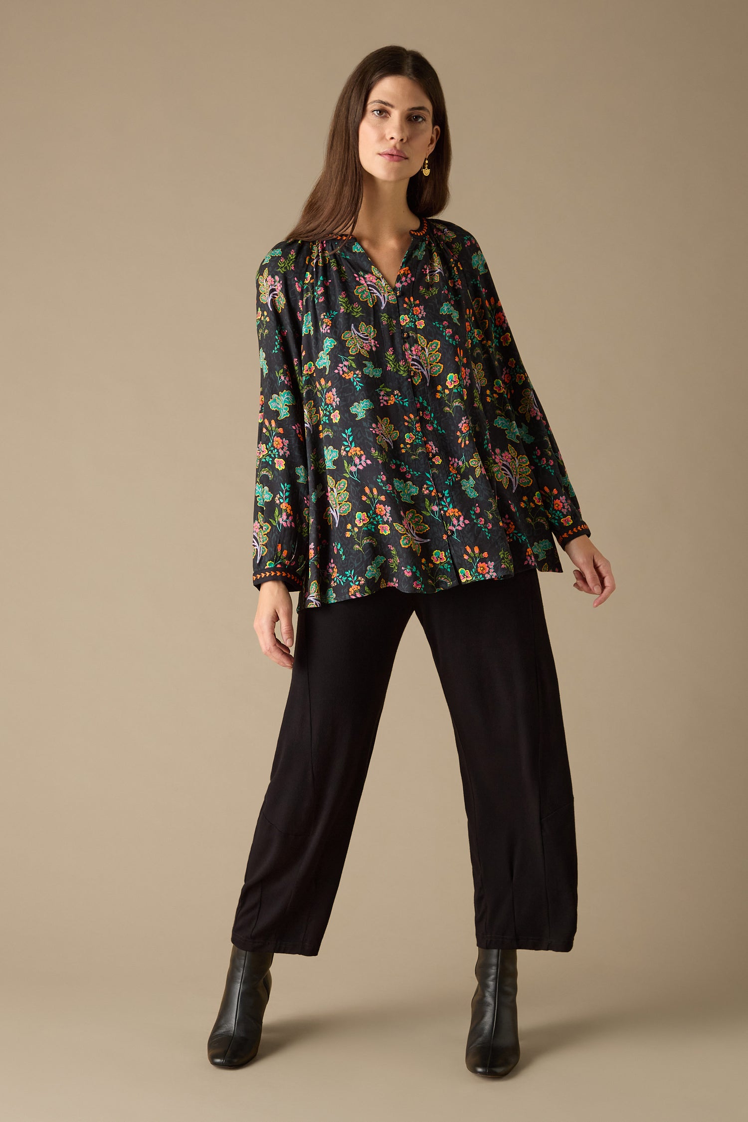 Dressed in a Hand Drawn Floral Boxy Shirt, complemented by black pants and black boots, an individual stands against a plain background, effortlessly showcasing their style.