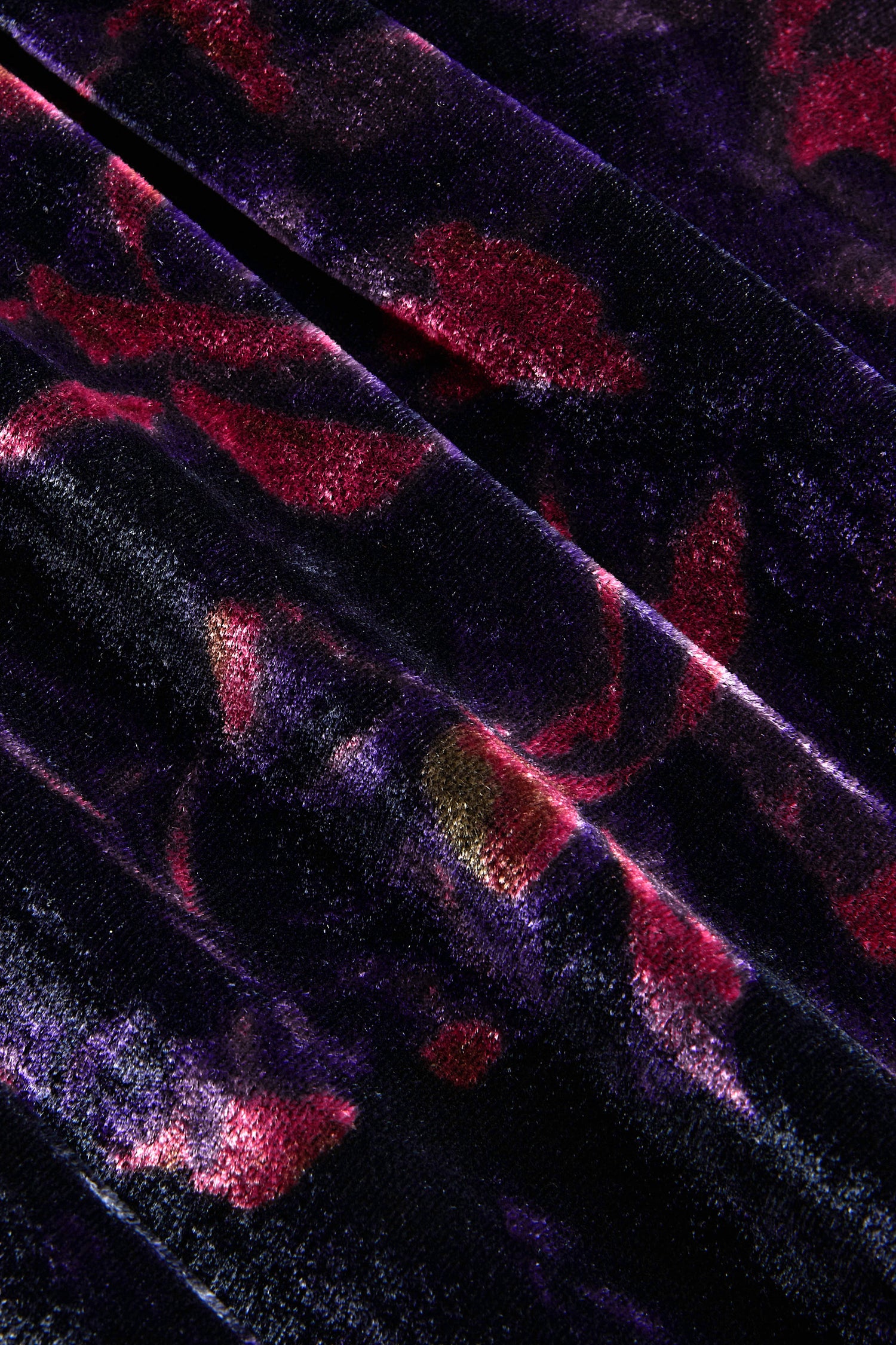 Close-up of a Midnight Peonies Velvet Tunic in folded dark purple fabric with a deep red and gold floral pattern.