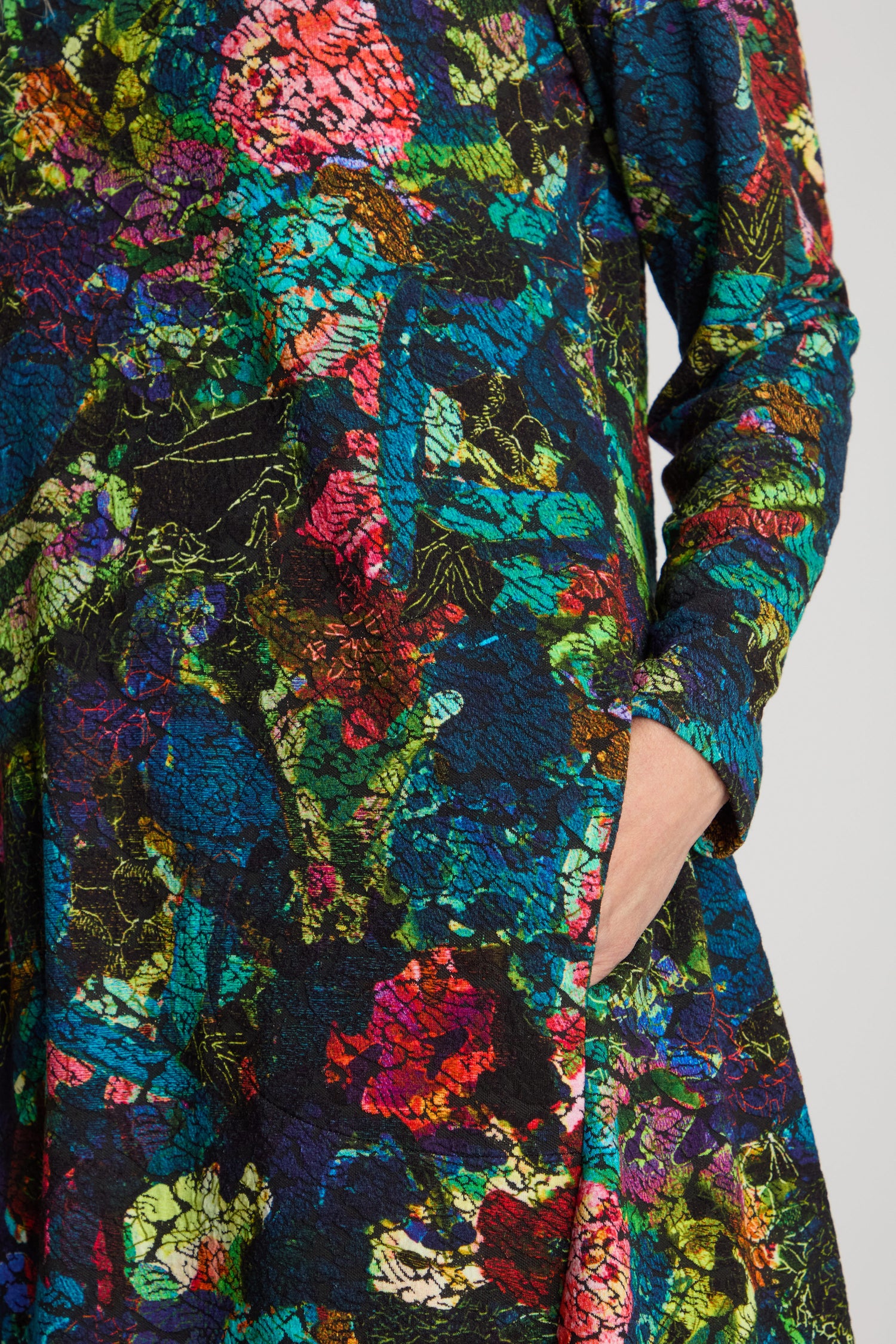 Close-up of a person wearing the Abstract Floral Jersey Bubble Dress with their right hand in the dress pocket.