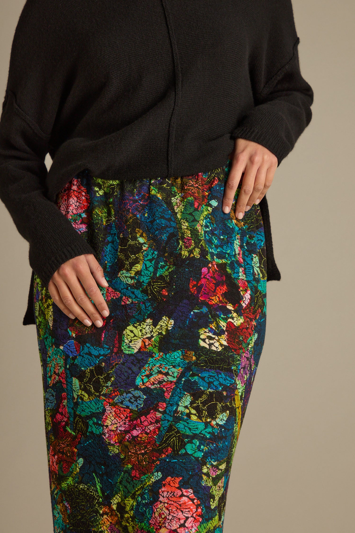 A person wearing a black sweater and the Abstract Floral Jersey Tube Skirt creates an eye-catching statement piece.