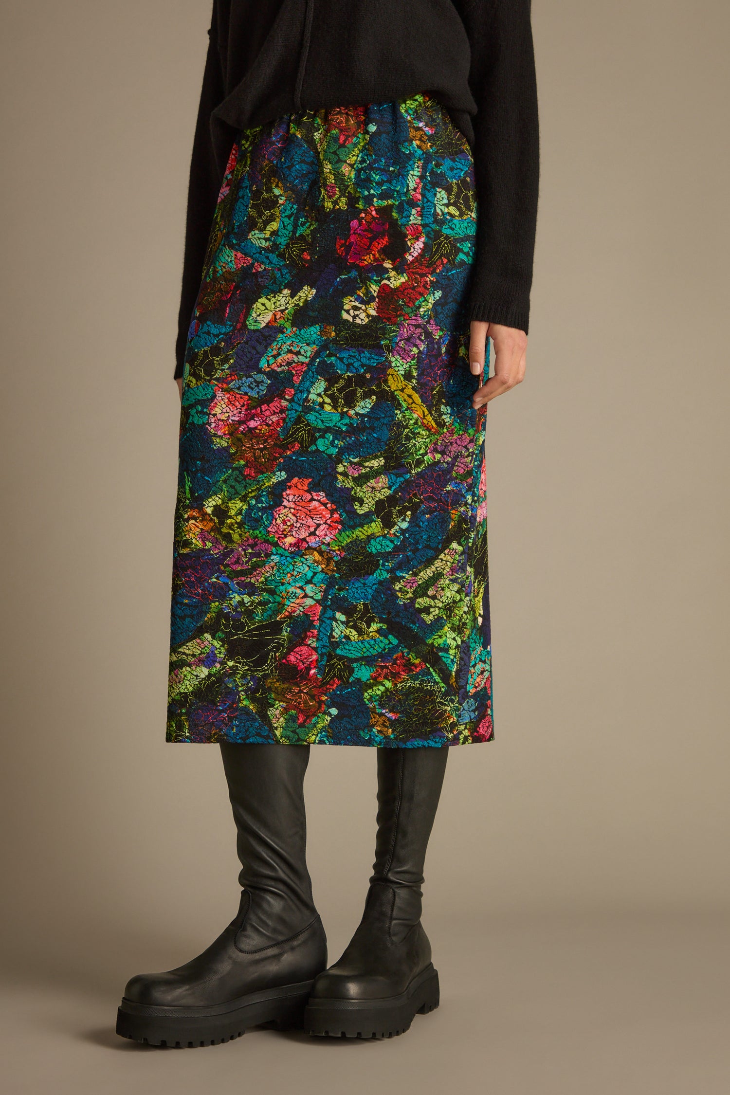 Person wearing the Abstract Floral Jersey Tube Skirt paired with black boots against a neutral background, creating a striking statement piece.