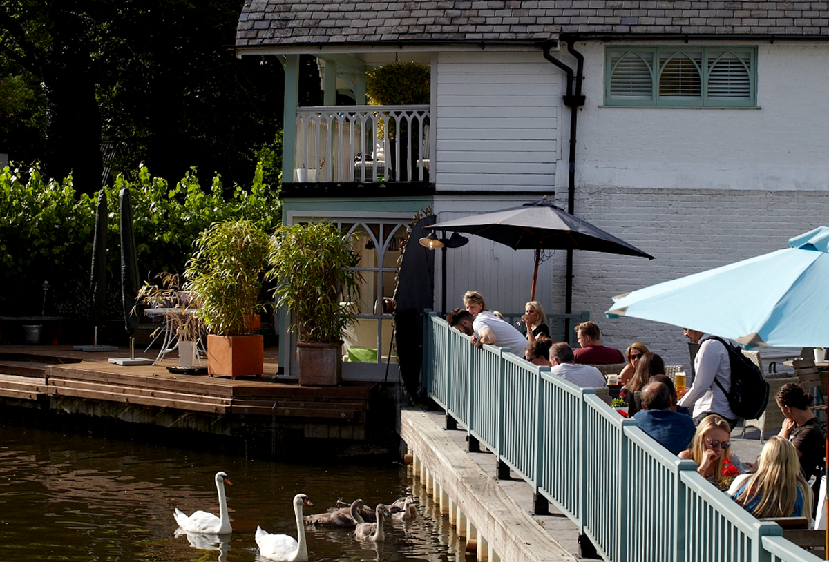 people in a beer garden next to a river