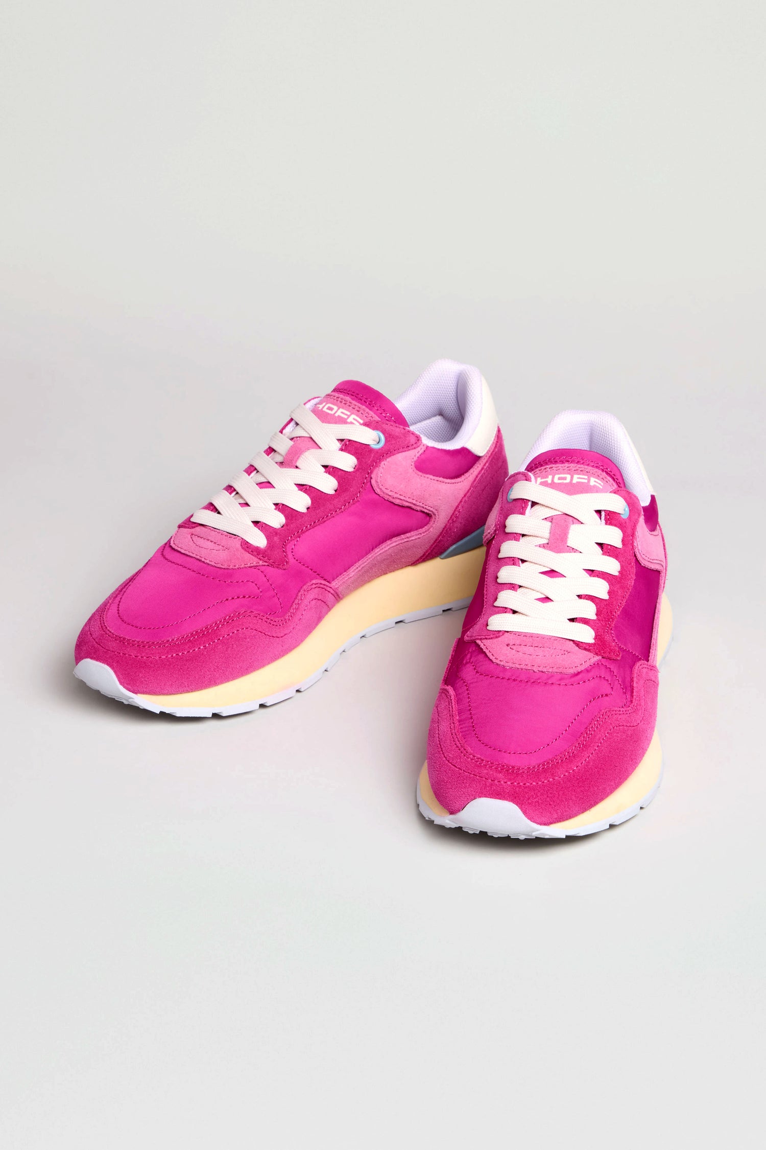 A pair of bright pink City Retro Trainers in suede and mesh with white laces, yellow midsoles, and white outsoles are displayed on a light background.
