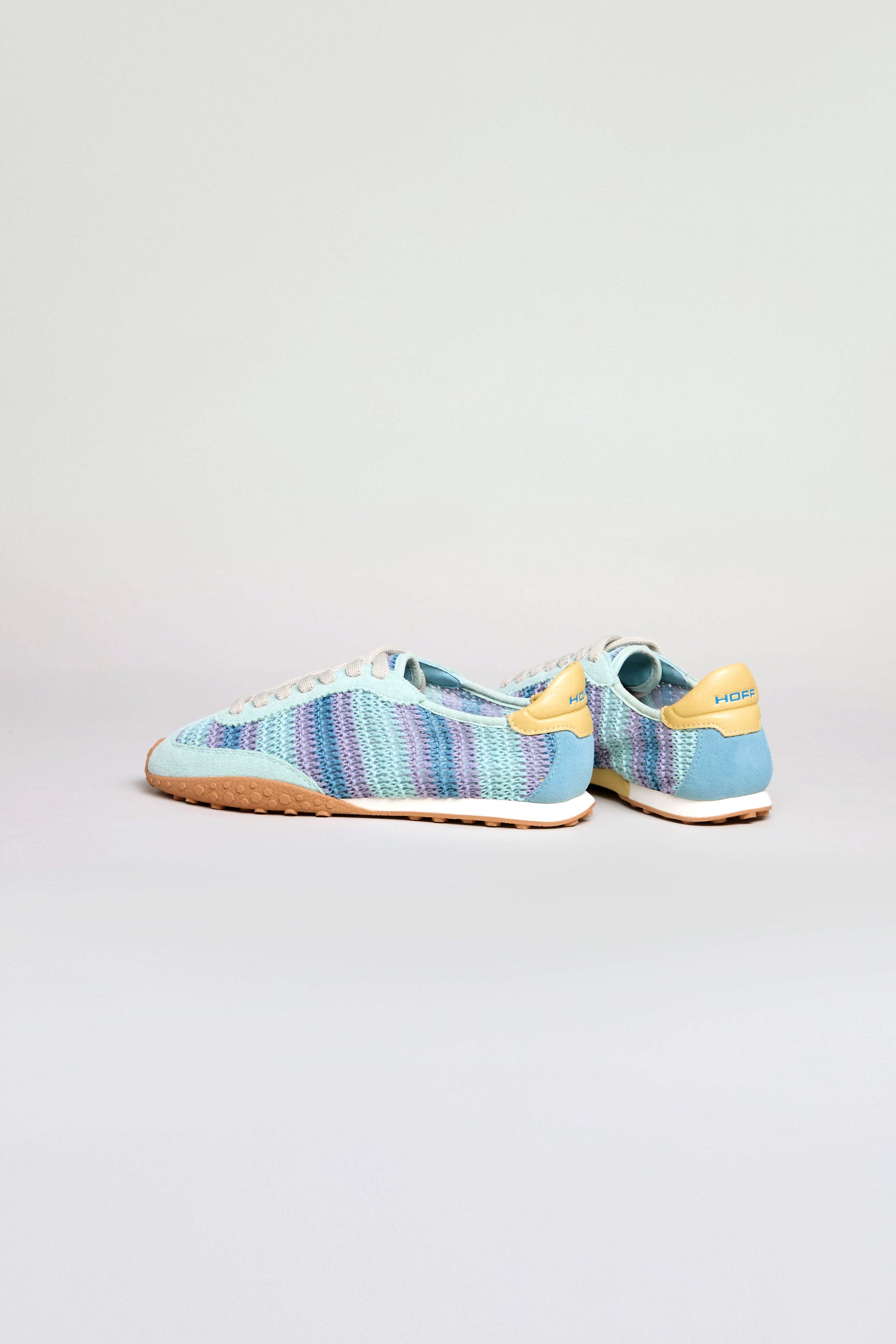 The Bridge Woven Light Blue Crochet Trainers feature a low-top design with blue, purple, and white crochet patterns, tan "HORIZON" heel tabs, a leather and crochet upper, and light brown cushioned soles against a plain background.