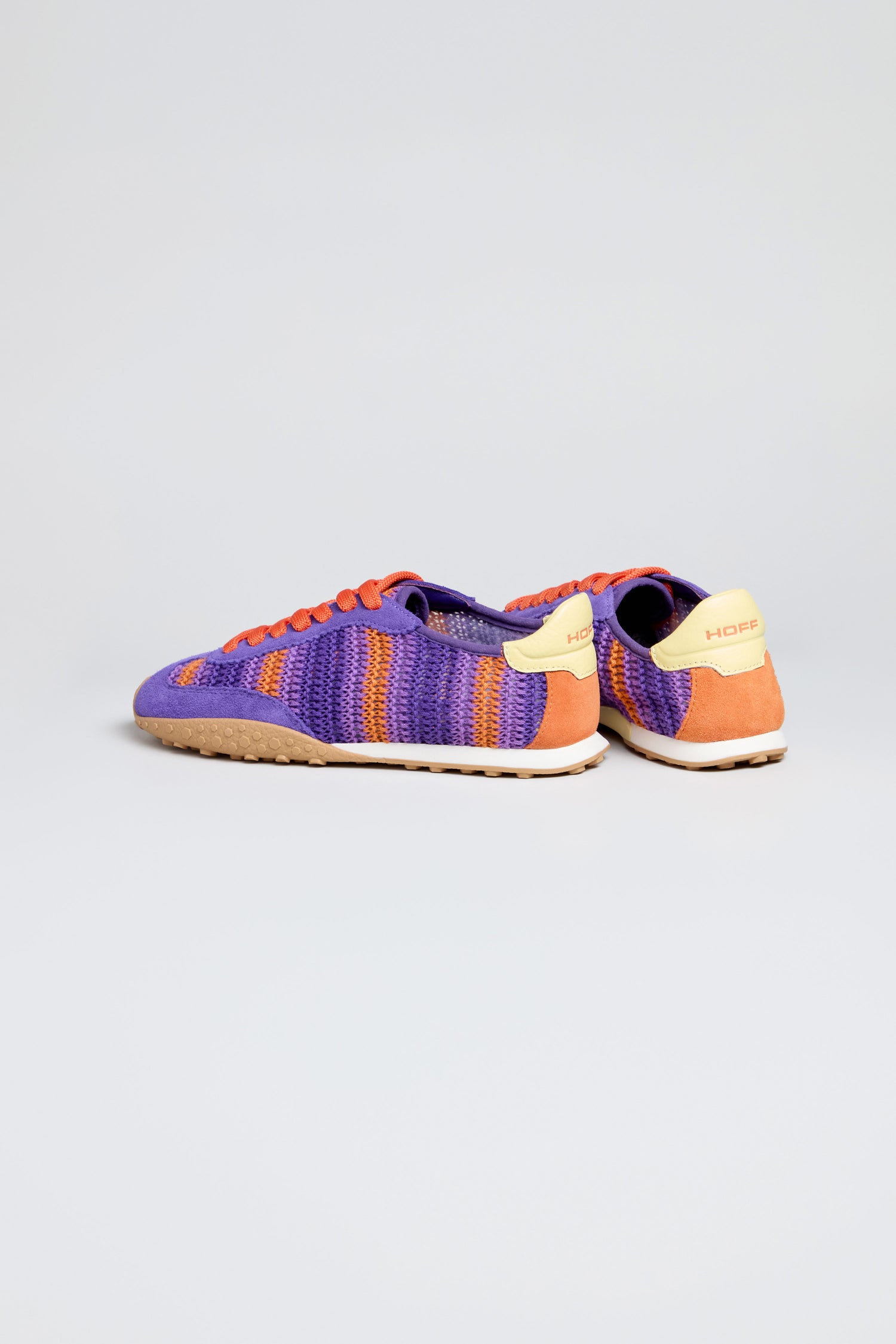 The Bridge Woven Purple Crochet Trainers feature purple, orange, and cream woven uppers, orange laces, and beige cushioned soles, displayed against a light grey background.