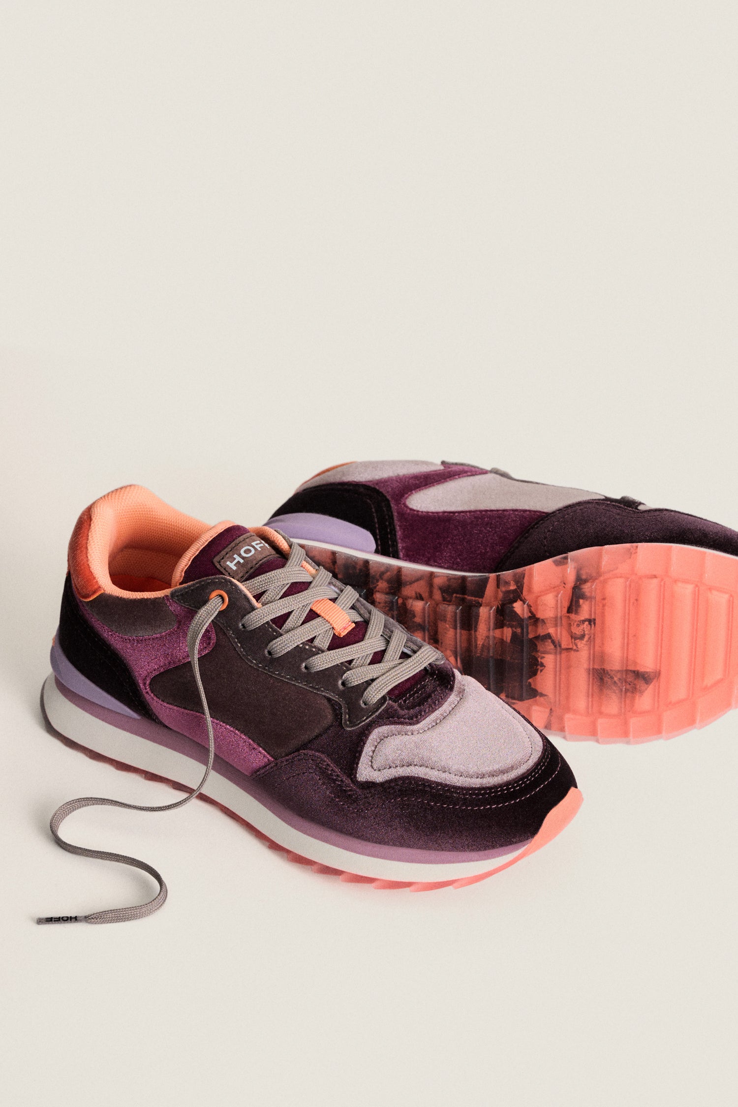 The Purple City Velvet Trainers are women’s casual shoes in burgundy and pink with gray laces, peach accents, and a marbled pink sole, shown against a plain light background.