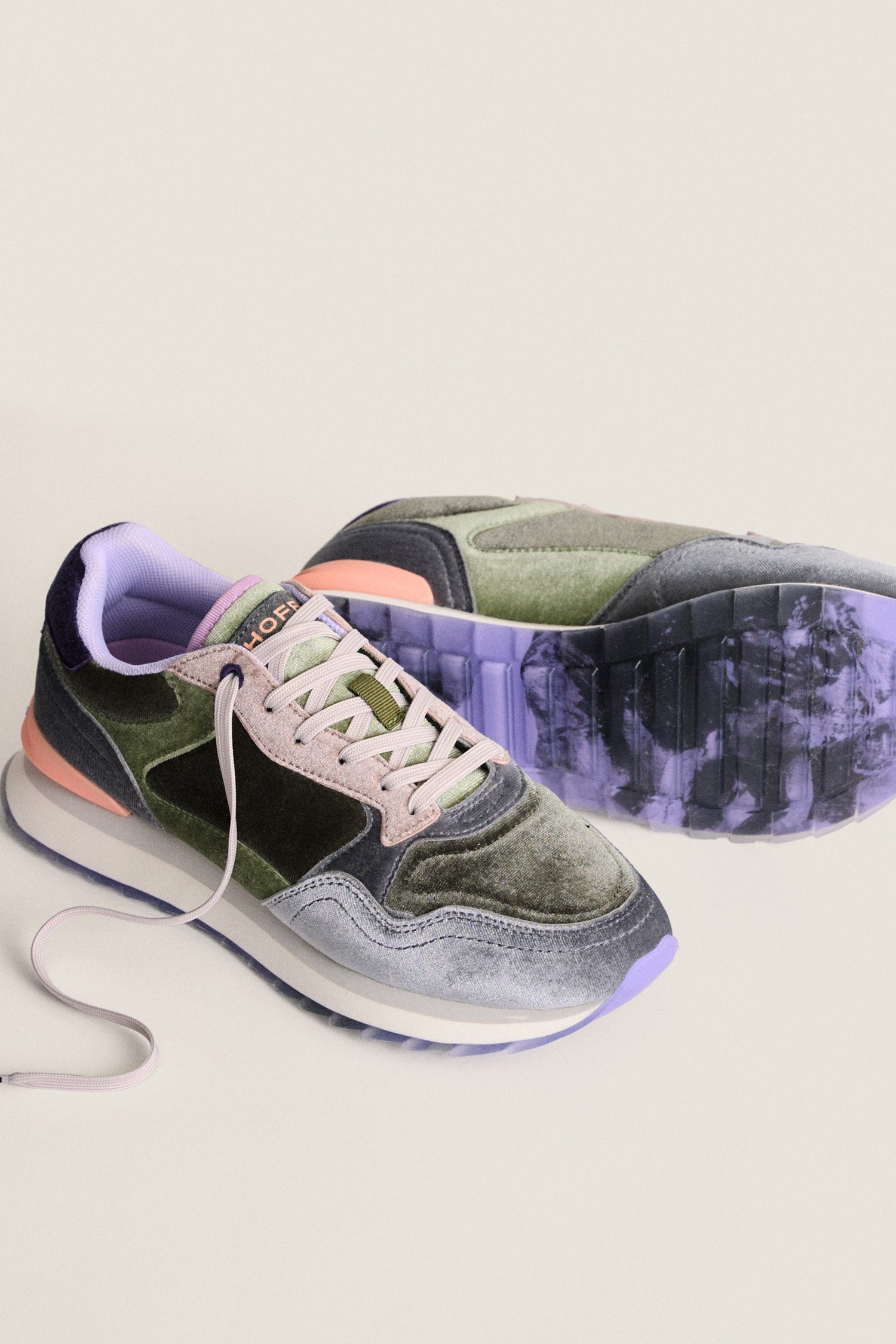 The Green City Velvet Trainers are stylish women’s lifestyle shoes featuring green, black, and purple accents, pink and white laces, and a purple-tinted sole, displayed on a light surface.