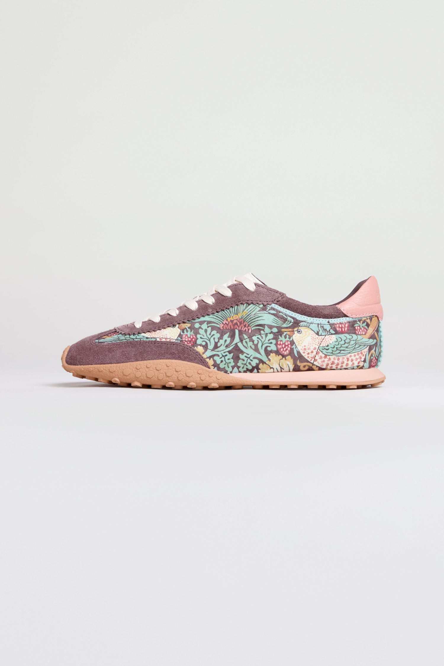 The William Morris Bridge Trainers are women’s leather trainers in mauve and pink, featuring a floral Strawberry Thief print, white laces, and a beige sole, displayed on a plain light background.