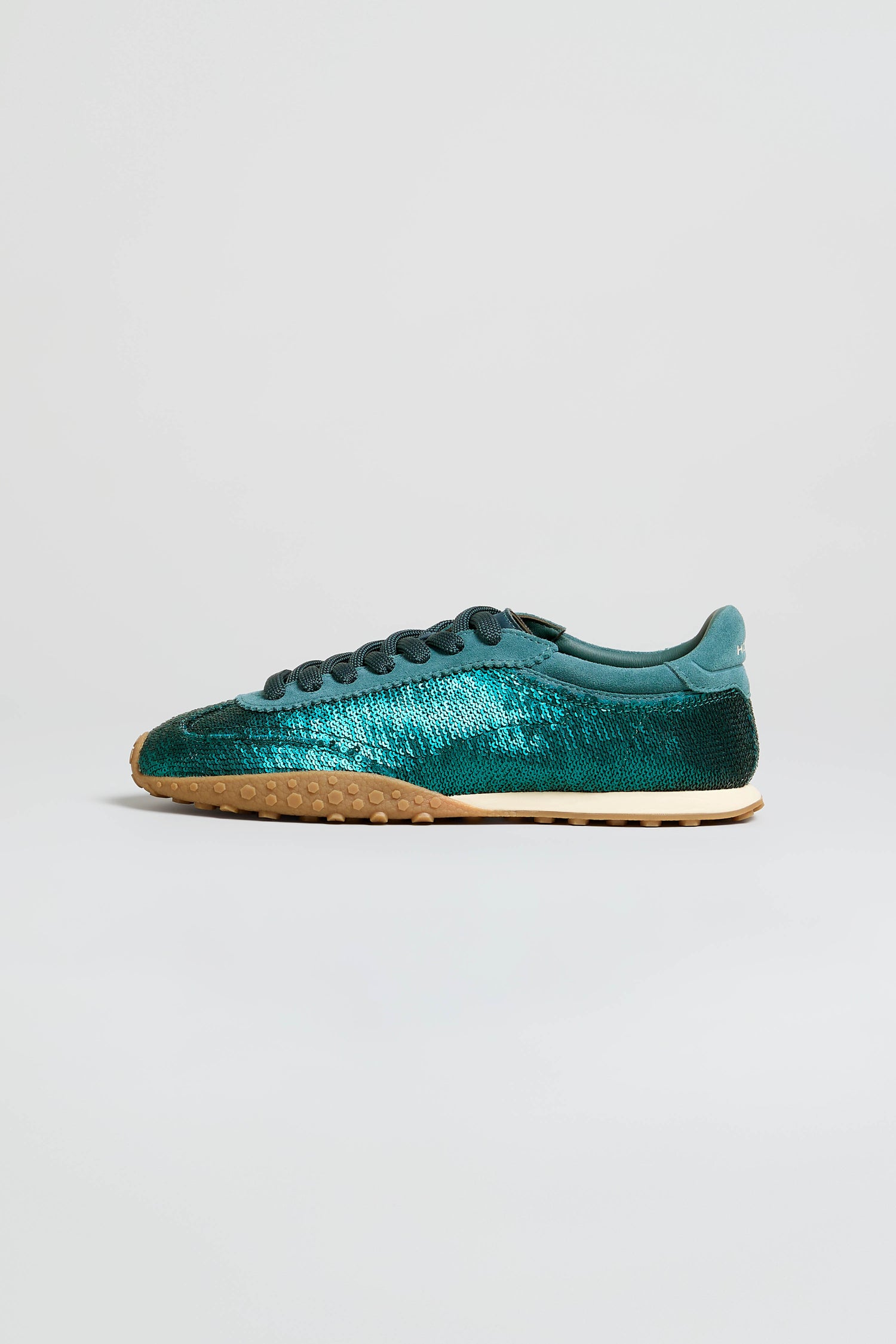 The Sequin Bridge Trainers, featuring a teal sequin-covered upper, black laces, a memory-foam insole, and a tan textured sole, are displayed on a plain white background.