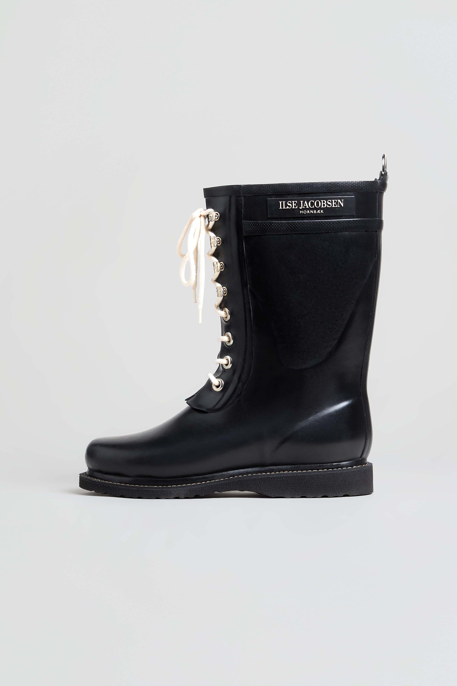 The Lace Up Wellington Boots, crafted from high-quality natural rubber, feature a black lace-up design with white laces and a prominent “ILSE JACOBSEN HORNBÆK” label on the shaft. Displayed against a plain light background, these stylish boots are an ideal choice for wet-weather wear.