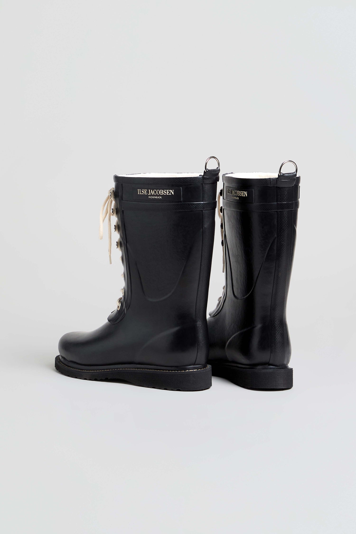 Lace Up Wellington Boots crafted from natural rubber, featuring a logo label near the top; one boot is shown facing forward while the other is angled slightly to the side, all set against a plain light background—stylish wet-weather footwear for any occasion.