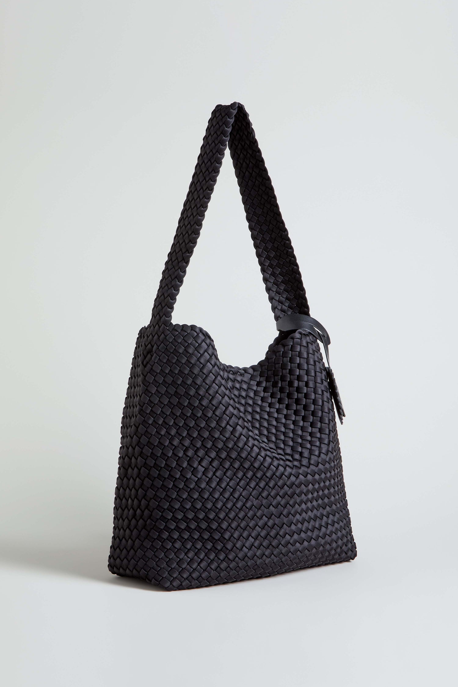 The Black Braided Shoulder Bag features a structured shape, wide strap, and simple design with intricate woven construction, shown against a plain white background.