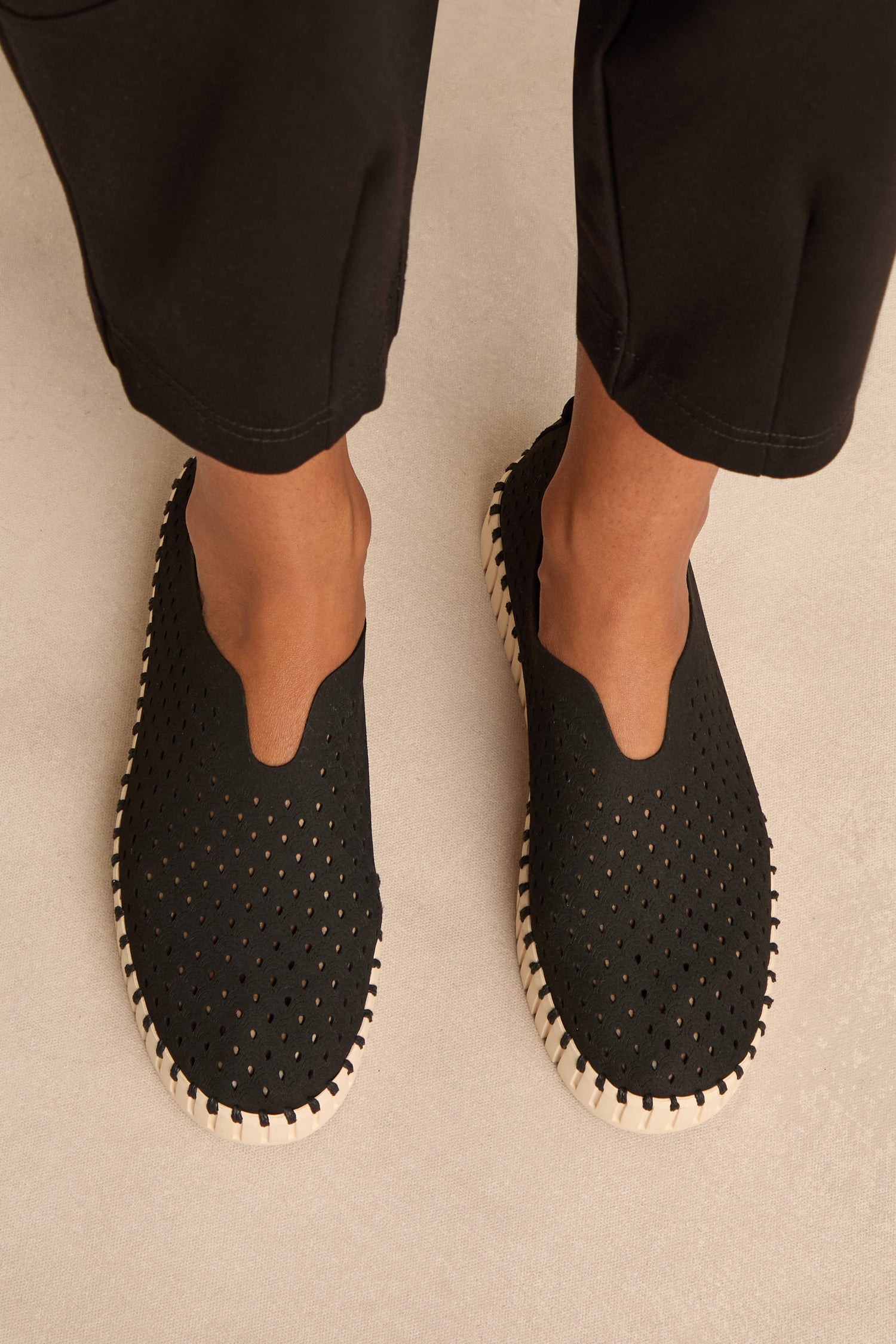 A person stands on a light-colored surface wearing Tulip Platform Slip On Shoes, featuring perforated uppers and white soles. Made from recycled microfiber, these breathable slip-ons provide comfort and style.