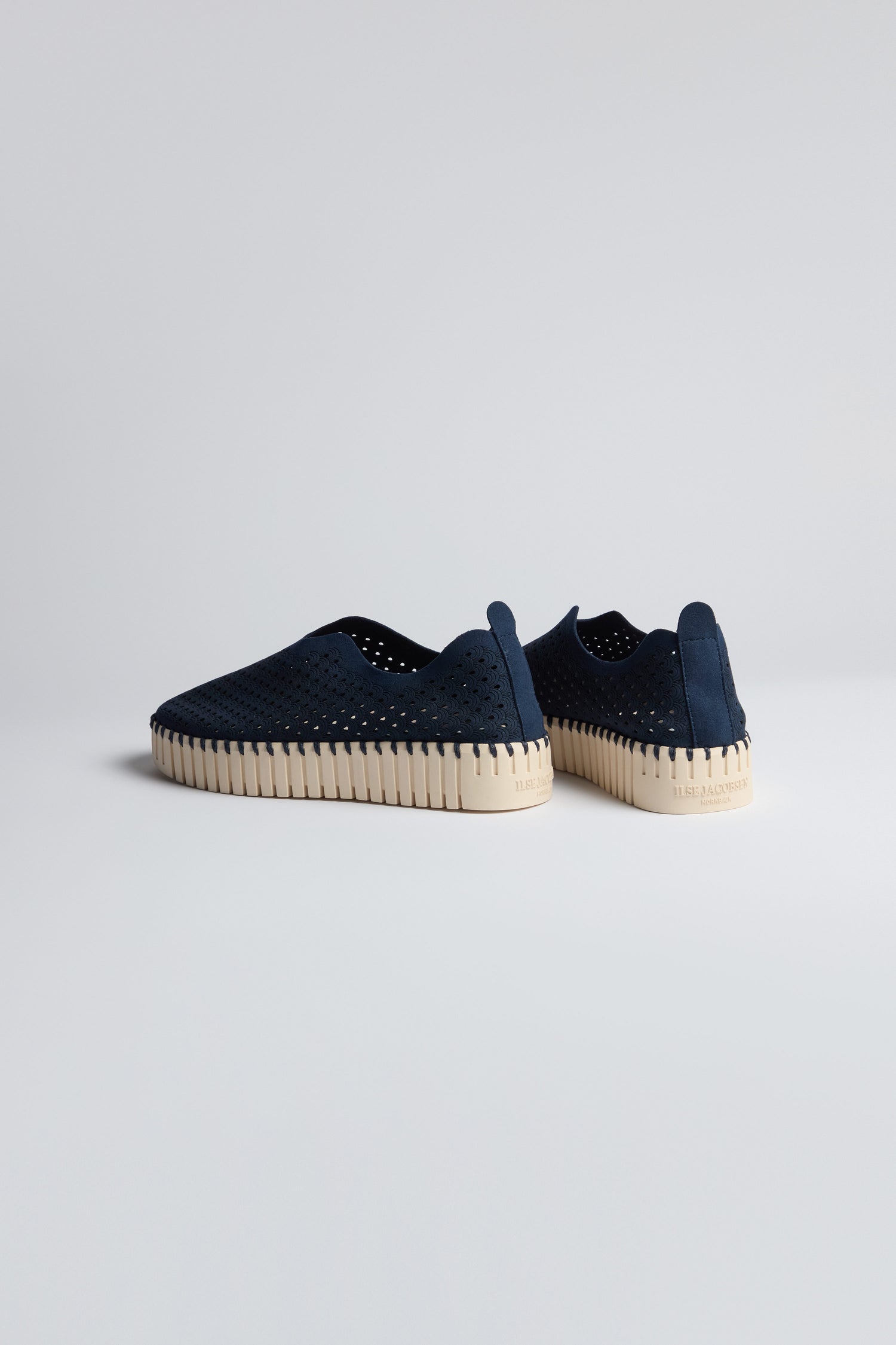 A pair of Indigo Tulip Platform Slip On Shoes with navy perforated uppers and light beige ribbed soles, made from recycled microfiber, displayed on a plain light background.