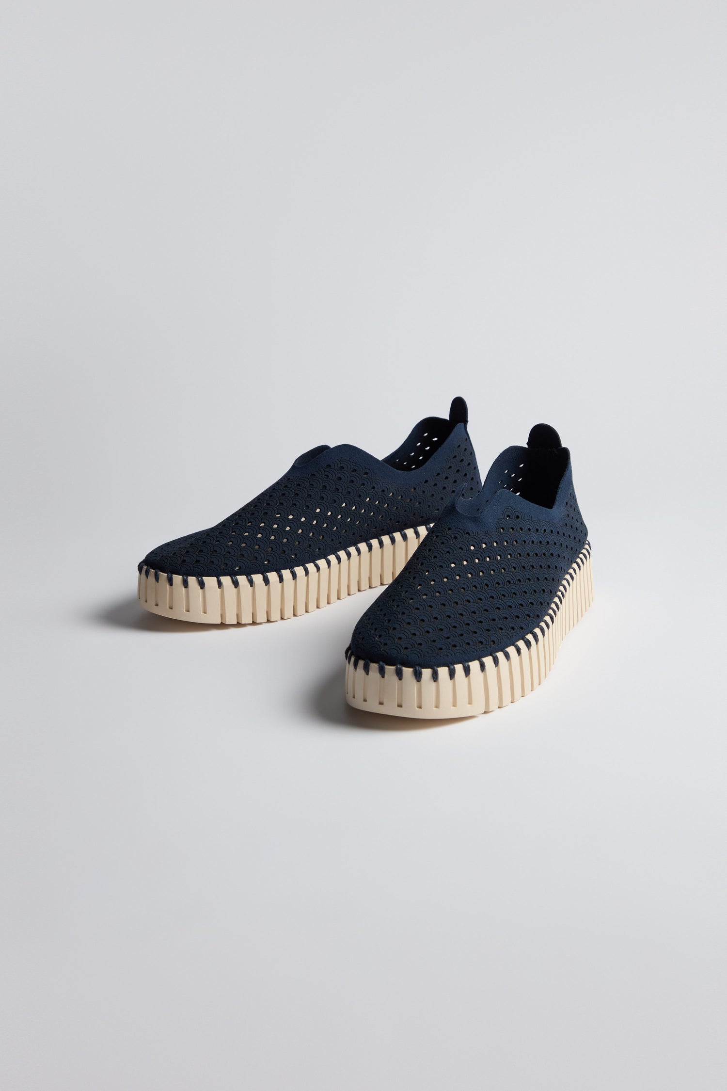 A pair of Indigo Tulip Platform Slip On Shoes featuring perforated recycled microfiber uppers and thick off-white textured soles, displayed on a plain light background.