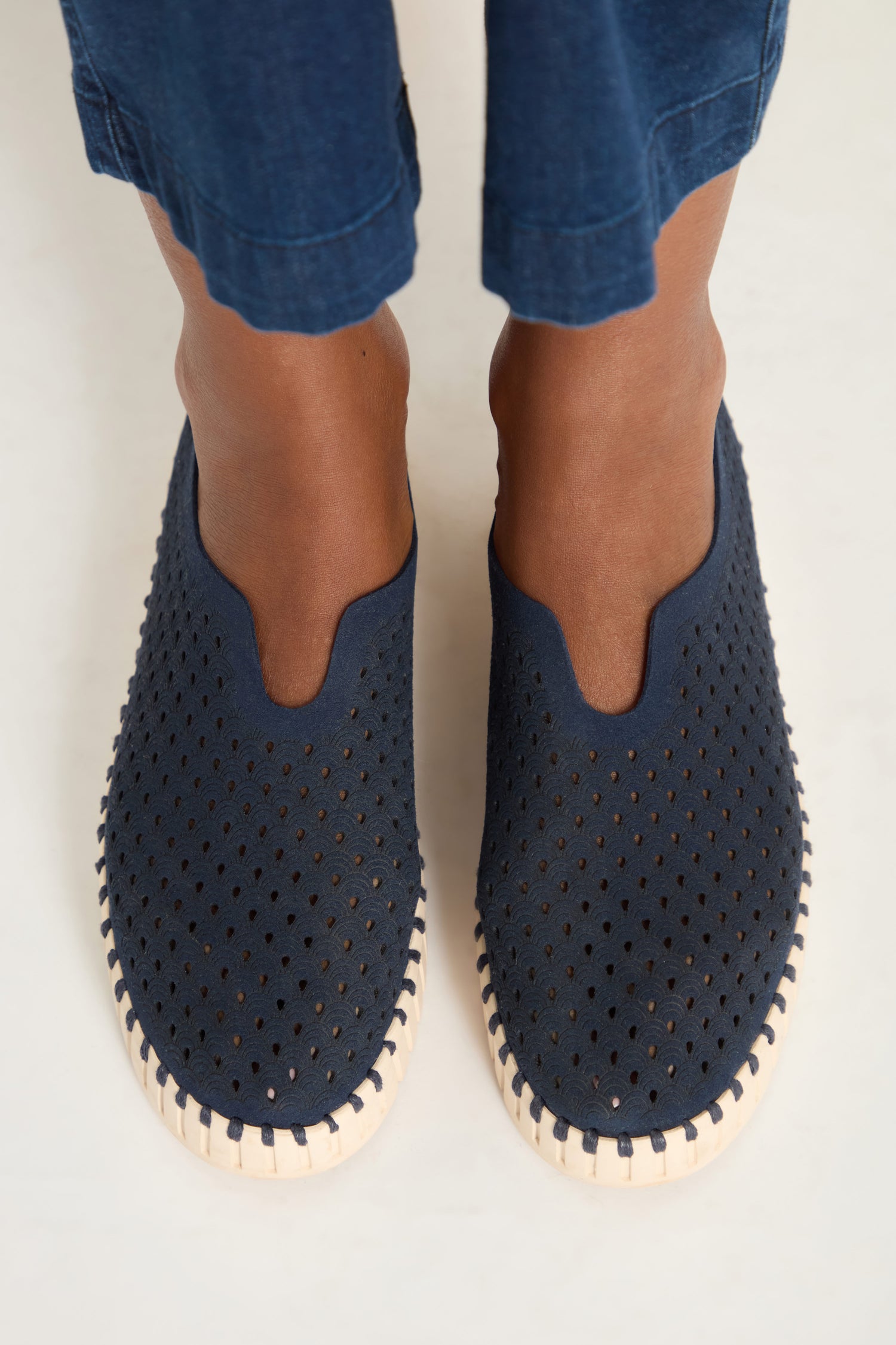 A person wearing Tulip Platform Slip on Shoes by Ilse Jacobsen, in dark blue recycled microfibre with white soles, stands on a light surface.
