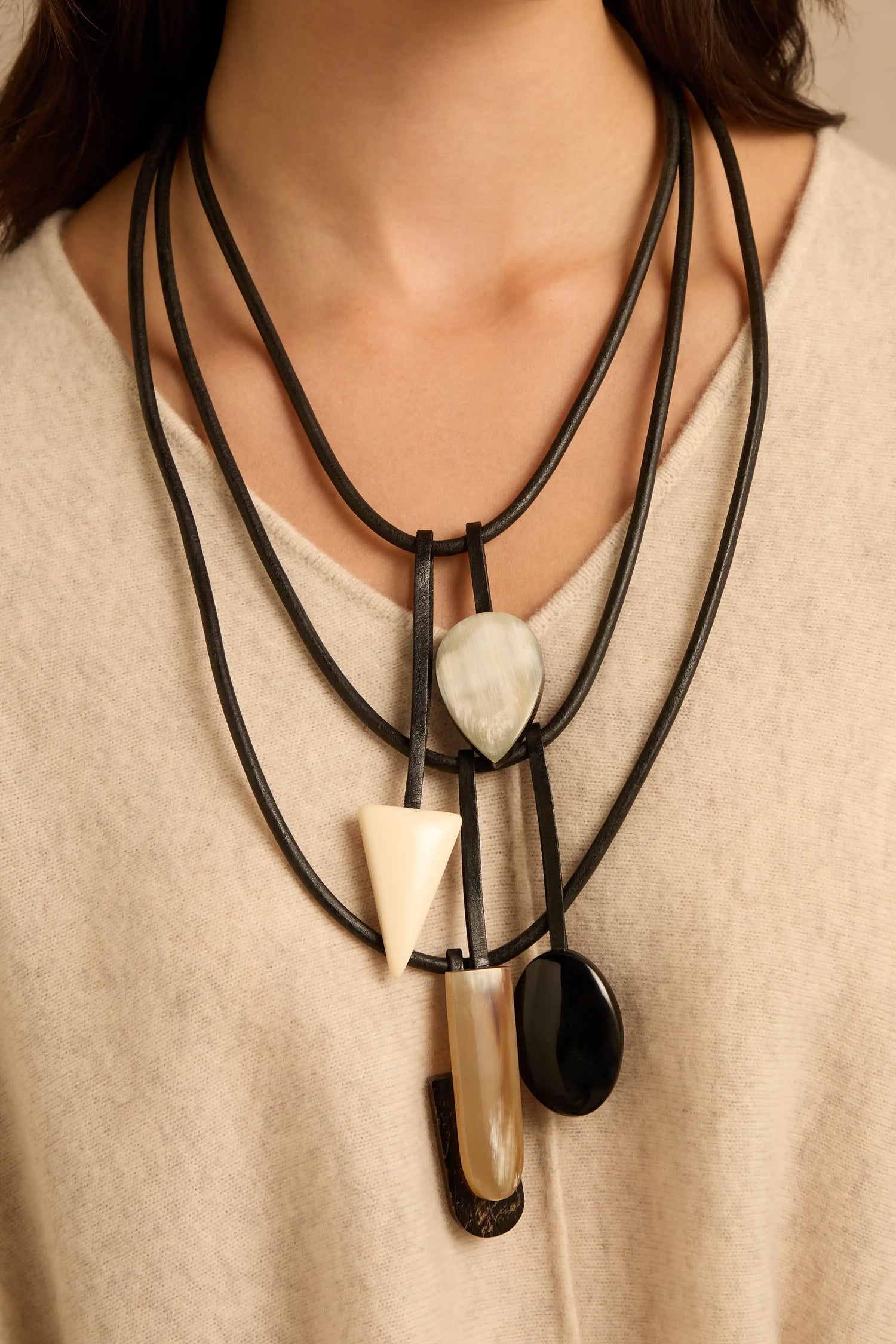 Buffalo Horn Elements Necklace featuring a multi-strand black leather cord with dangling buffalo horn pendants in teardrop, triangle, and circular shapes.