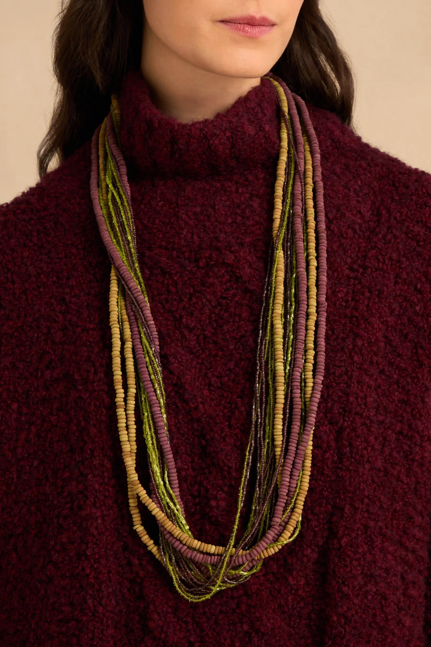 Mango Wood & Bead Waterfall Necklace featuring multi-strand layers of thin, colorful beads in shades of mustard yellow, olive green, and plum.