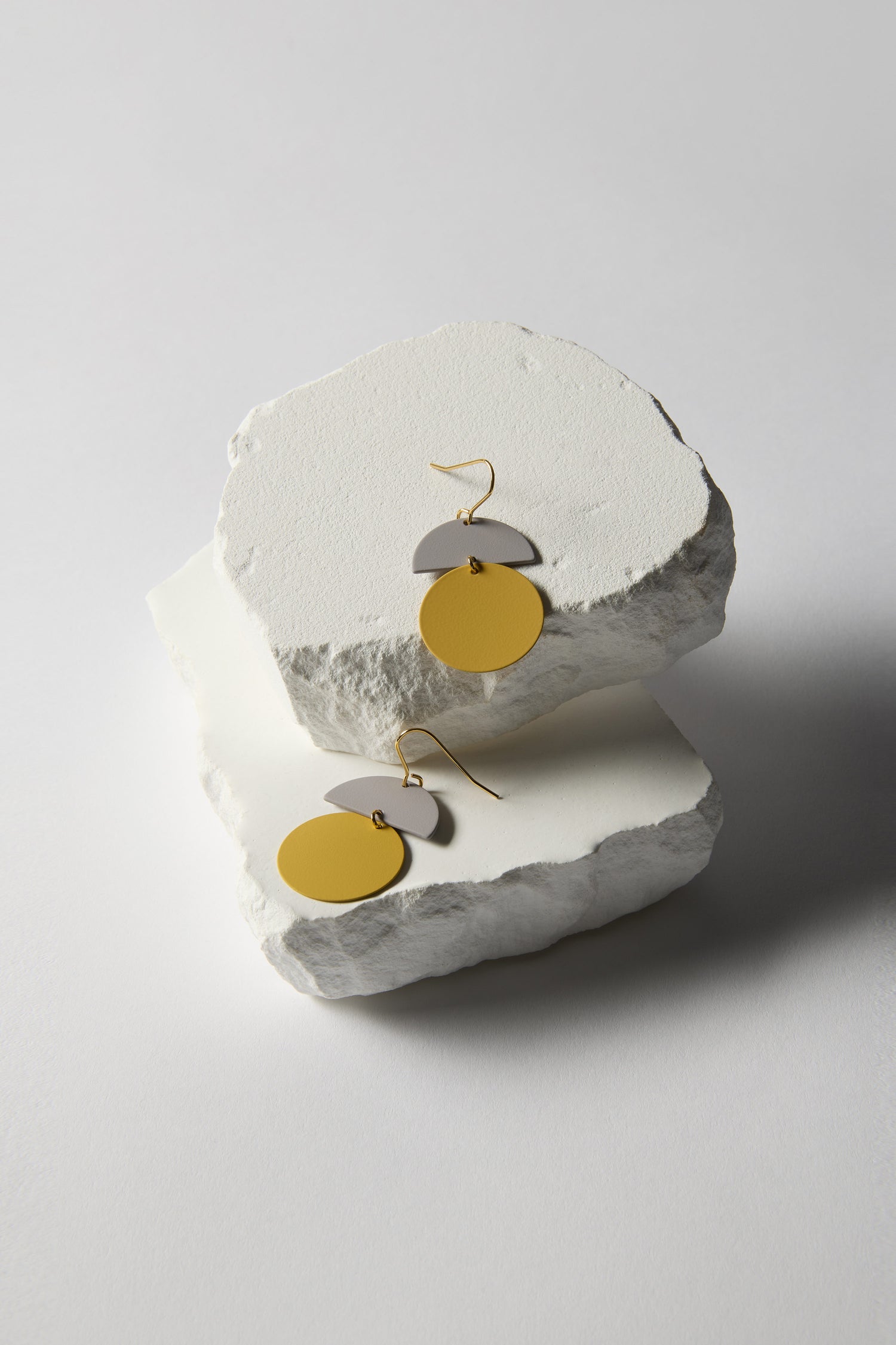 Discover the charm of the Colour Pop Circle Drop Earrings, featuring yellow circular and gray semicircular elements on textured white stone blocks. Ideal for statement jewelry lovers, they add a vibrant touch to any outfit.