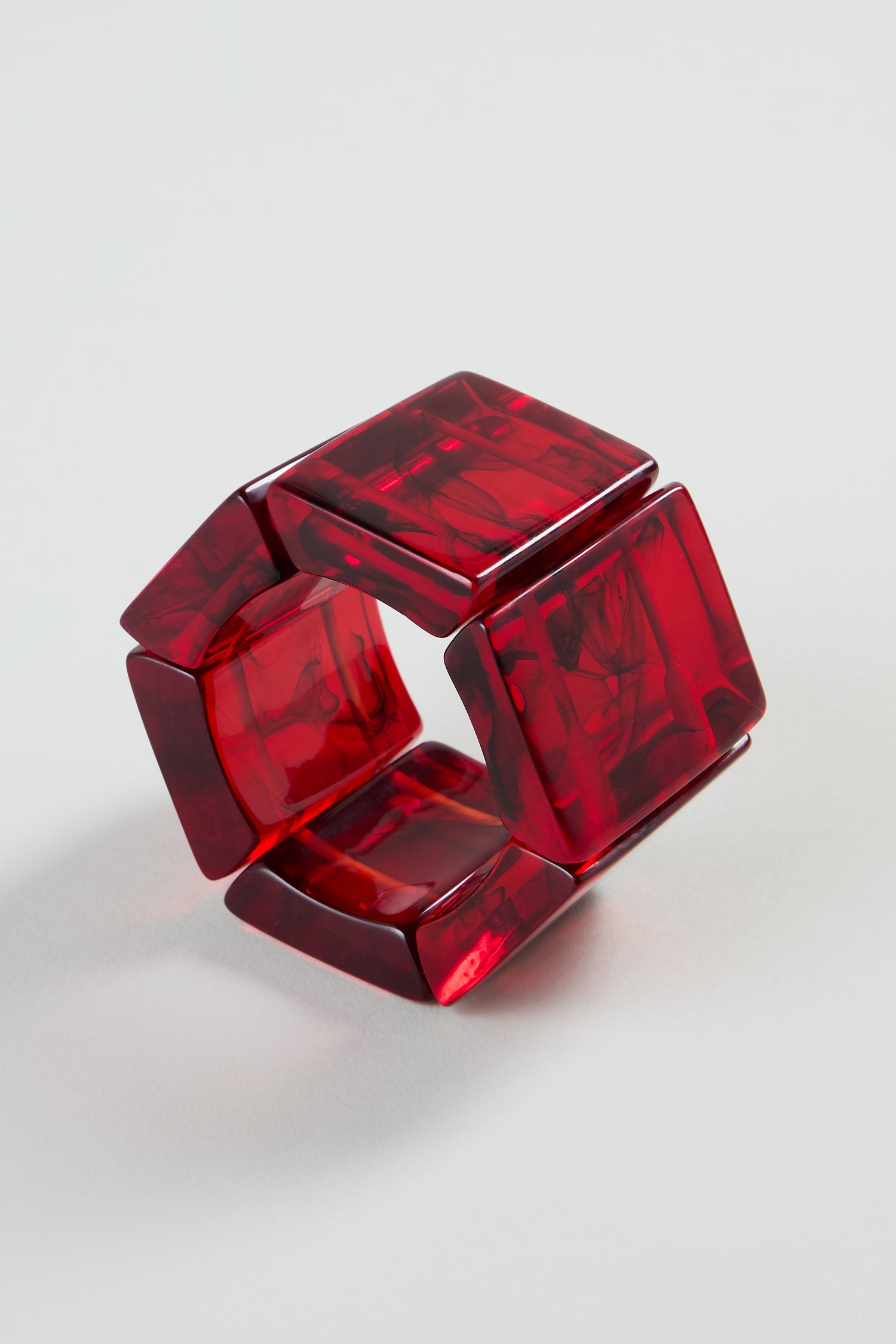 The Ruby Resin Bracelet by Jackie Brazil features chunky red geometric marbled square panels arranged in a circle, showcased on a plain light background.