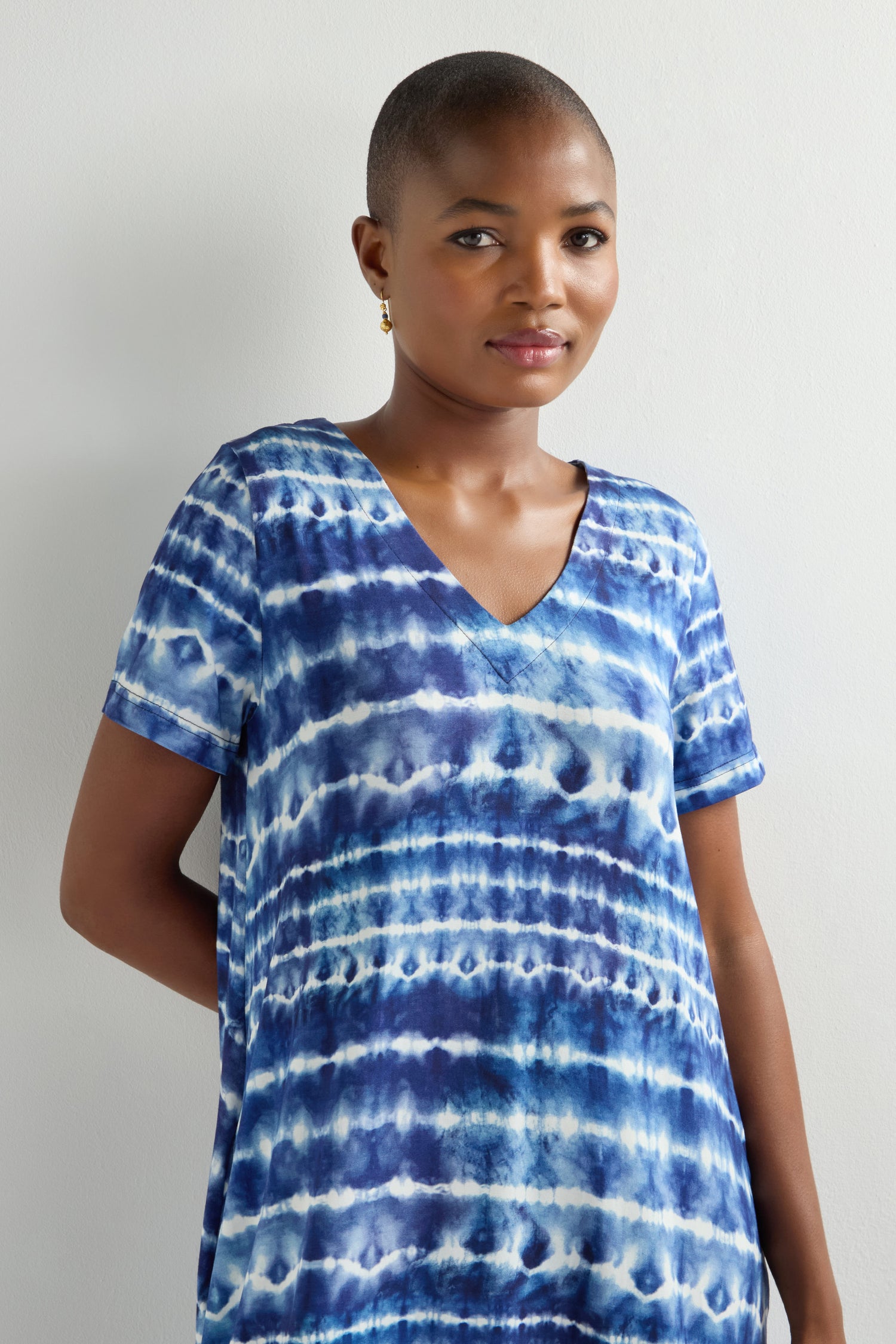 Donning a blue and white Tie Dye Jersey Bubble Dress, an individual effortlessly stands against a plain white background, exuding a relaxed look.
