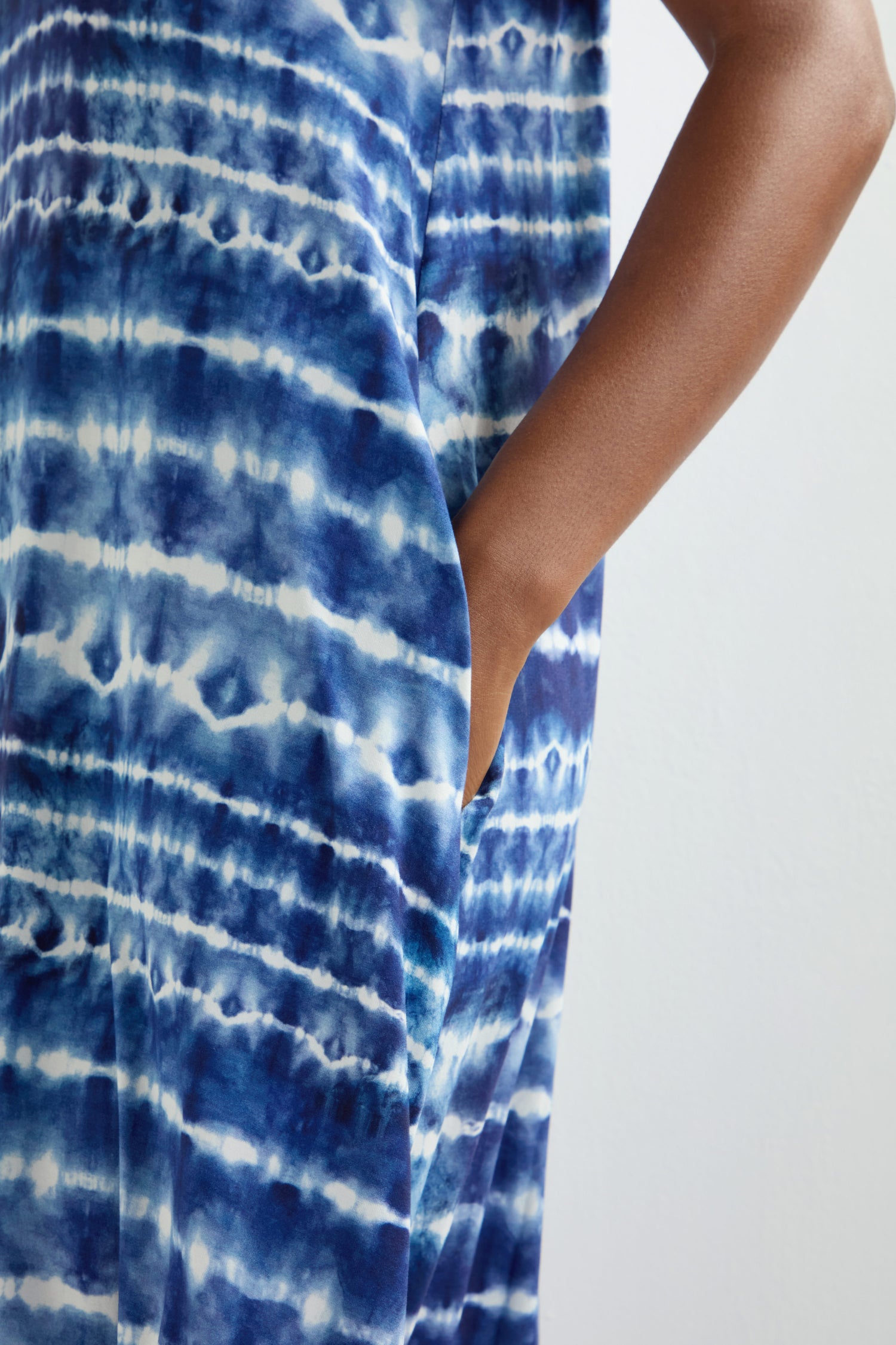 A person is wearing the Tie Dye Jersey Bubble Dress in a blue and white tie-dye pattern, with one hand resting in the pocket. Its classic fit and midi length create an effortlessly chic look.