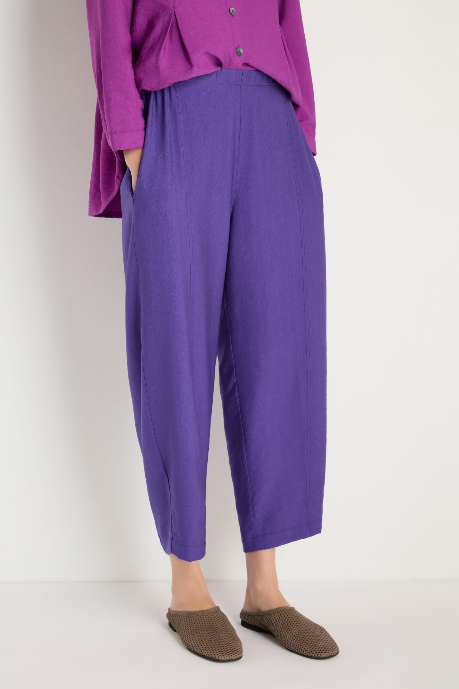 Person wearing Textured Viscose Bubble Trouser in purple, featuring a loose fit and cropped length, paired with a matching long-sleeve top and brown slip-on shoes, standing against a plain light background.