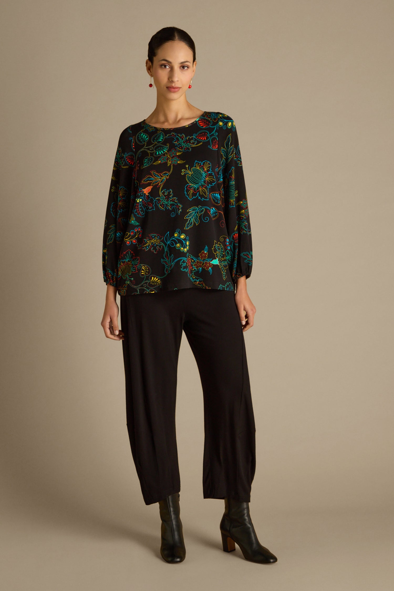 A person wearing the Bright Dotted Floral Jersey Top with an oversized fit, black pants, and heeled boots stands against a plain background.