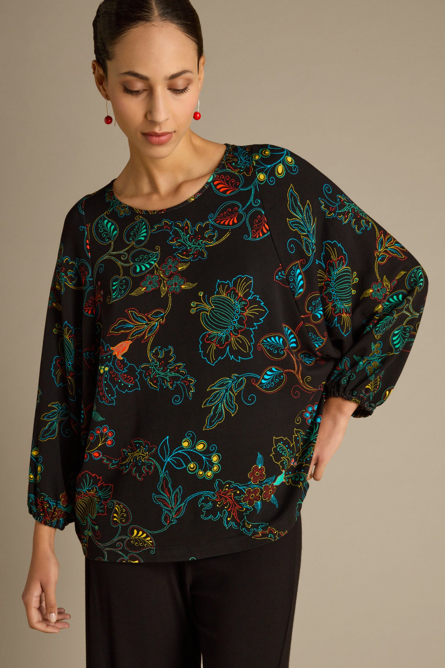 A person wearing a Bright Dotted Floral Jersey Top paired with black pants stands against a plain background.
