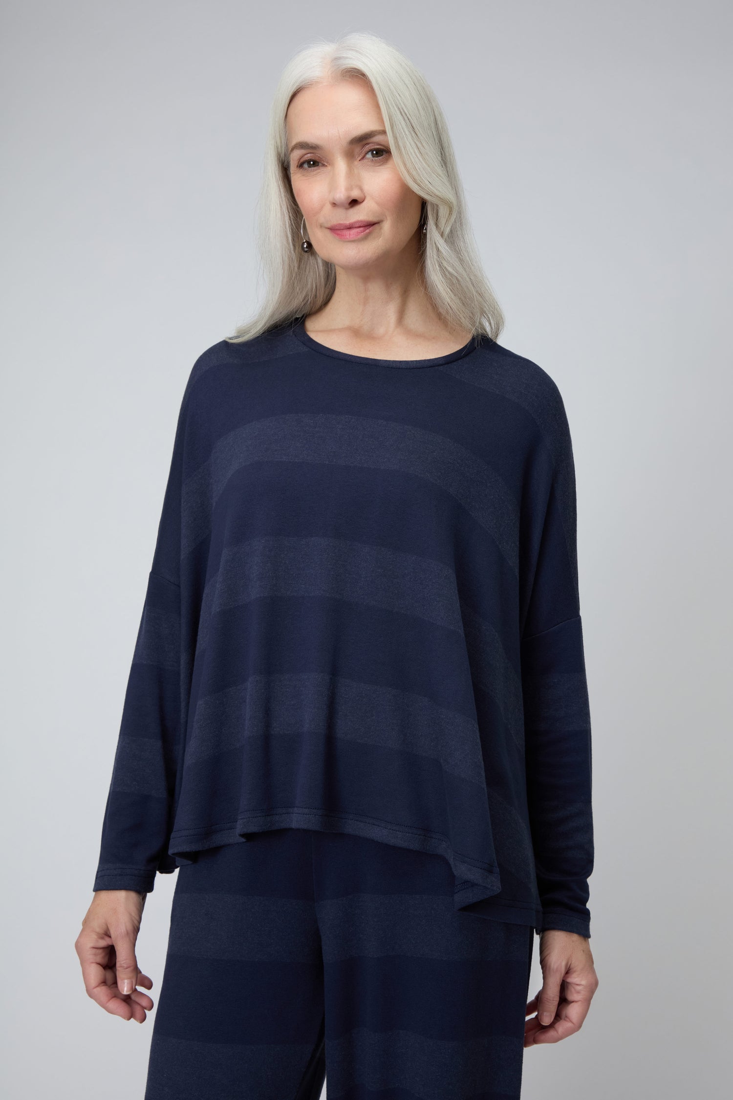 A woman with long gray hair wears the Soft Viscose Jersey Stripe Boxy Top and matching pants. Made in England, the outfit stands out against a plain light background.