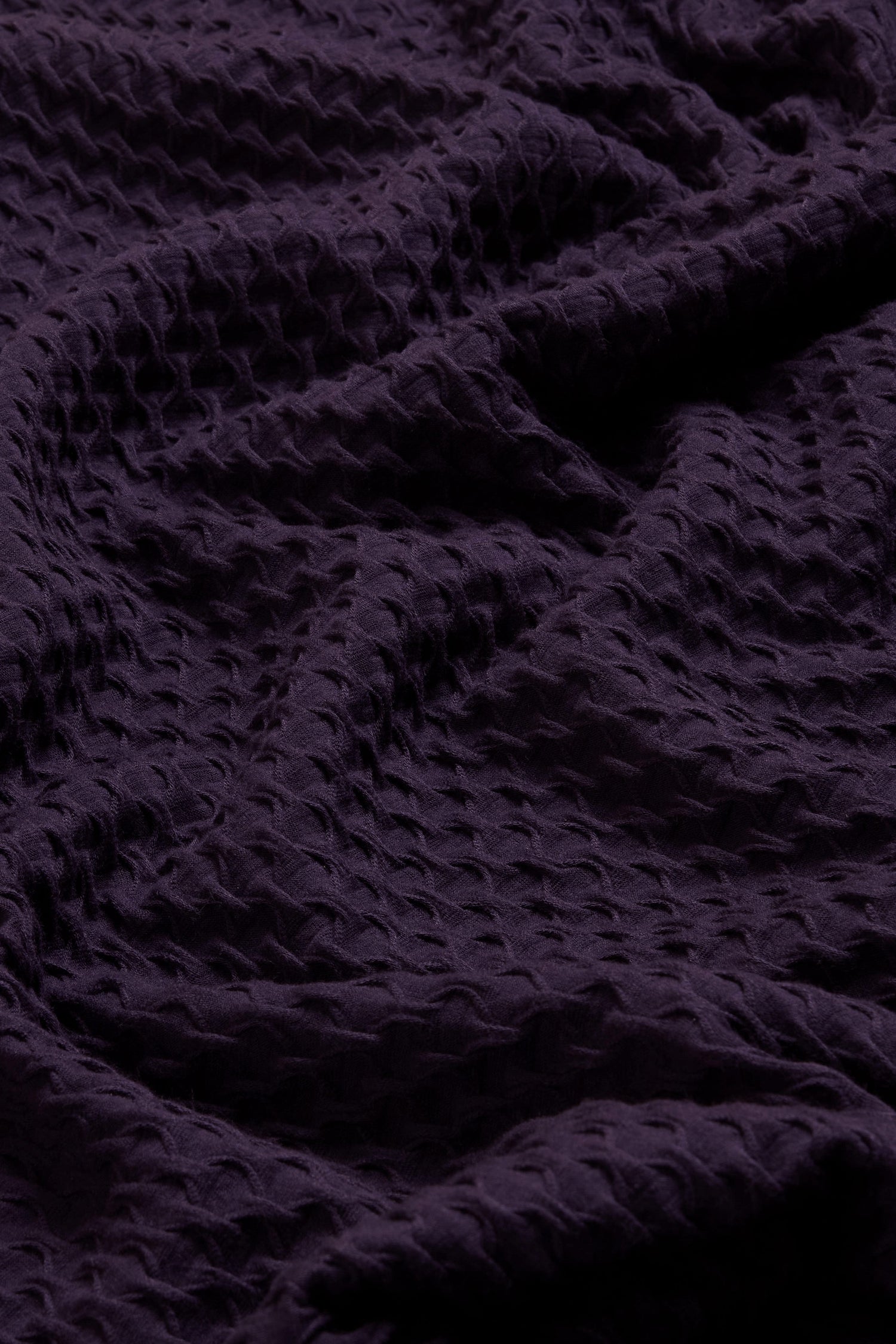 Close-up of the Waffle Textured Jersey Damson Cowl Neck Top, showcasing its deep purple hue, distinctive waffle-like texture, and softly draped folds—ideal for a chic cowl neck silhouette.