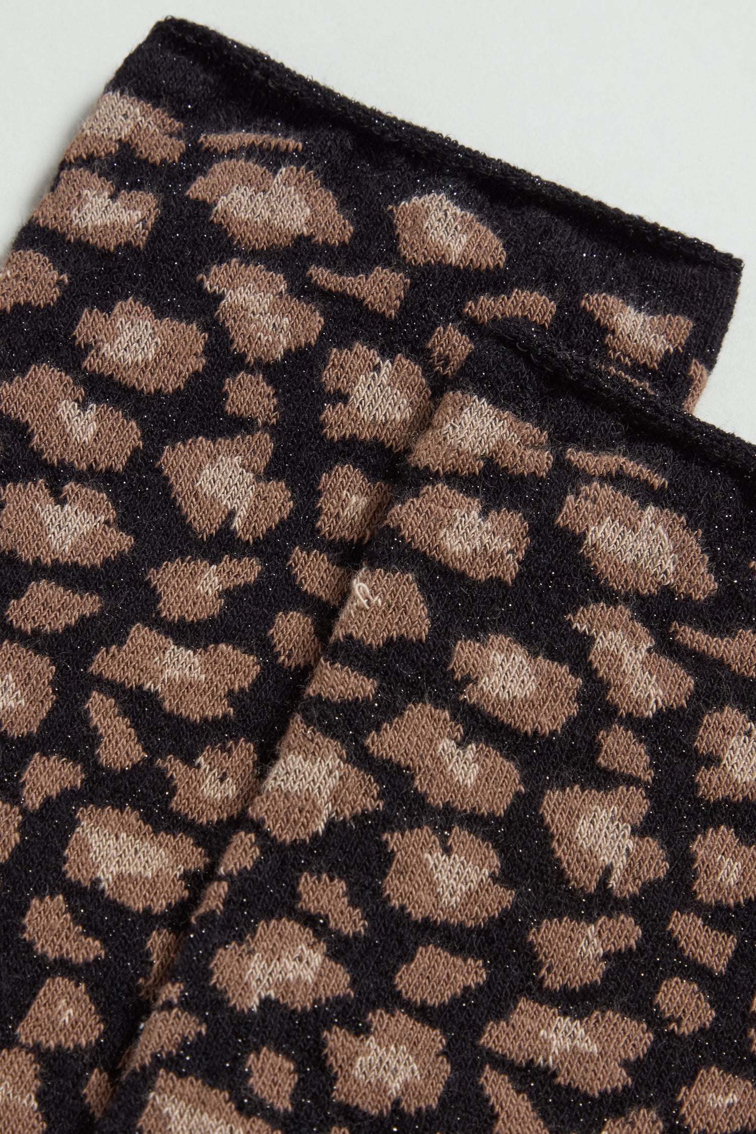 Close-up of two pieces of brown and black leopard print fabric on a light background—ideal for making eco-friendly socks like our Bamboo Leopard Black Print Socks.