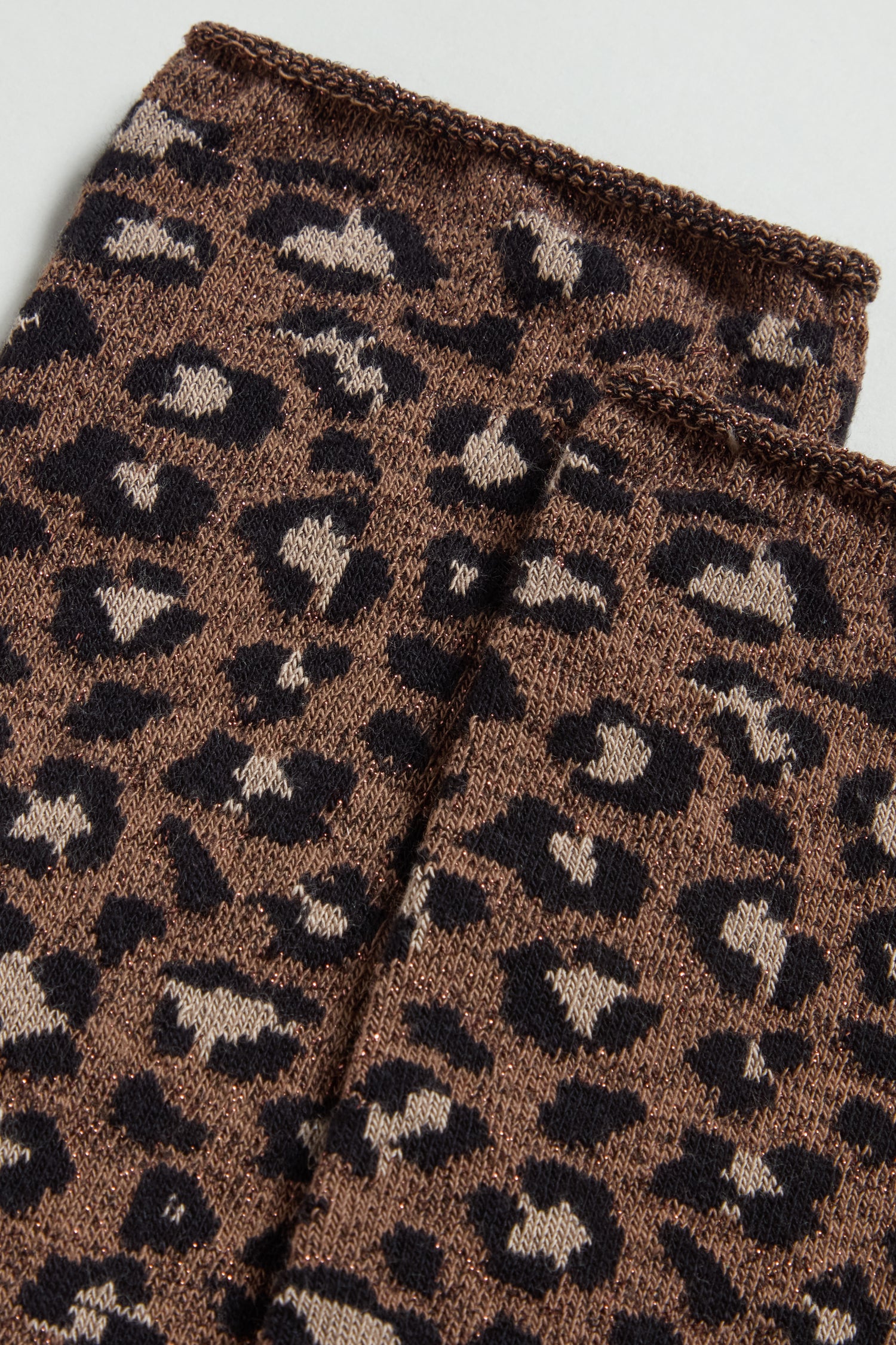 Close-up view of brown fabric with black and beige leopard spots and visible stitching, featured on Bamboo Leopard Brown Print Socks—perfect for sustainable style lovers.