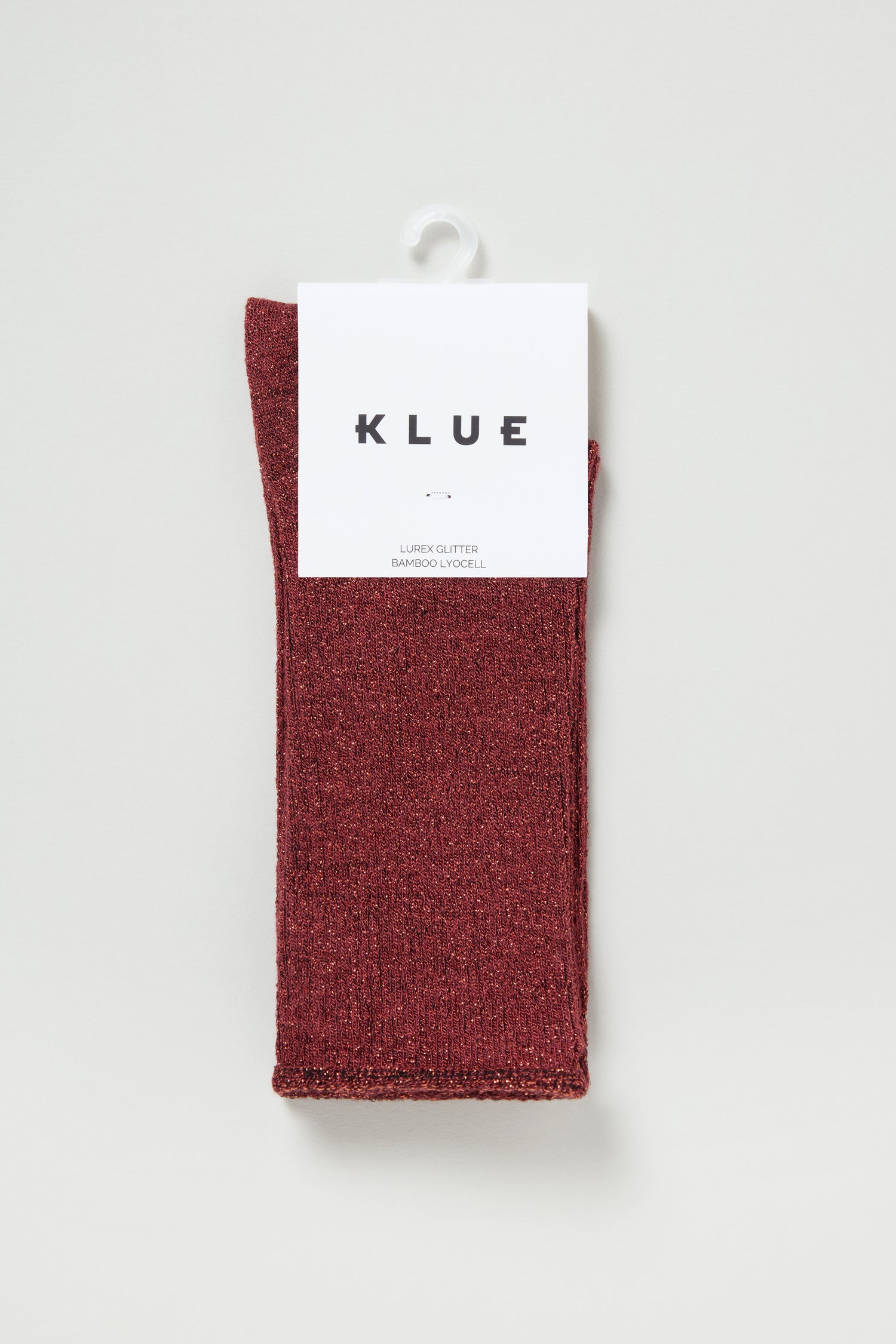 A pair of folded Bamboo Sparkle Red Socks in "KLUE" packaging, shown against a light backdrop—ideal for anyone seeking sustainable socks with a touch of red glitter.