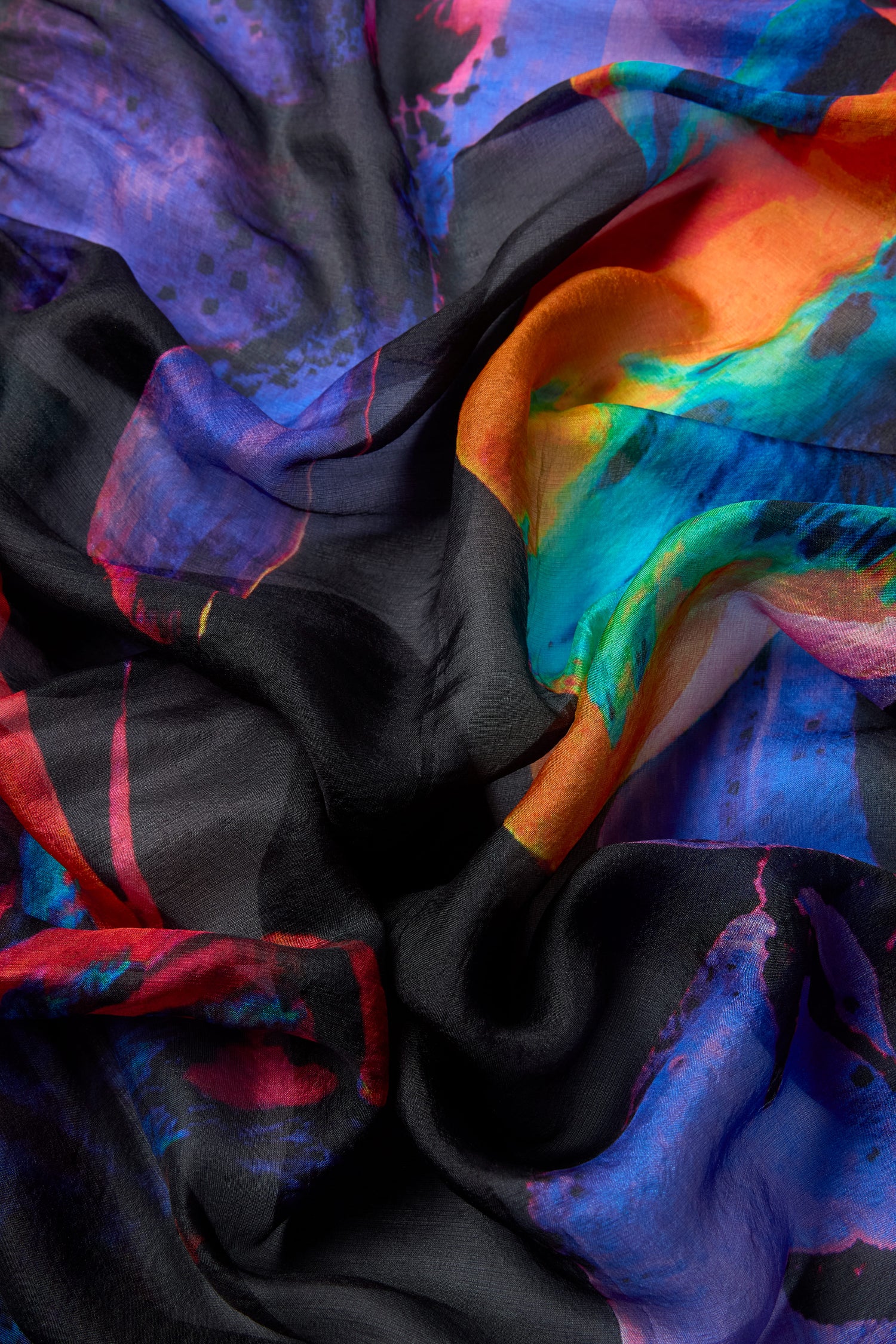 Close-up of the Orchid Silk Scarf featuring a vibrant abstract pattern with swirling shades of blue, purple, red, orange, and black.