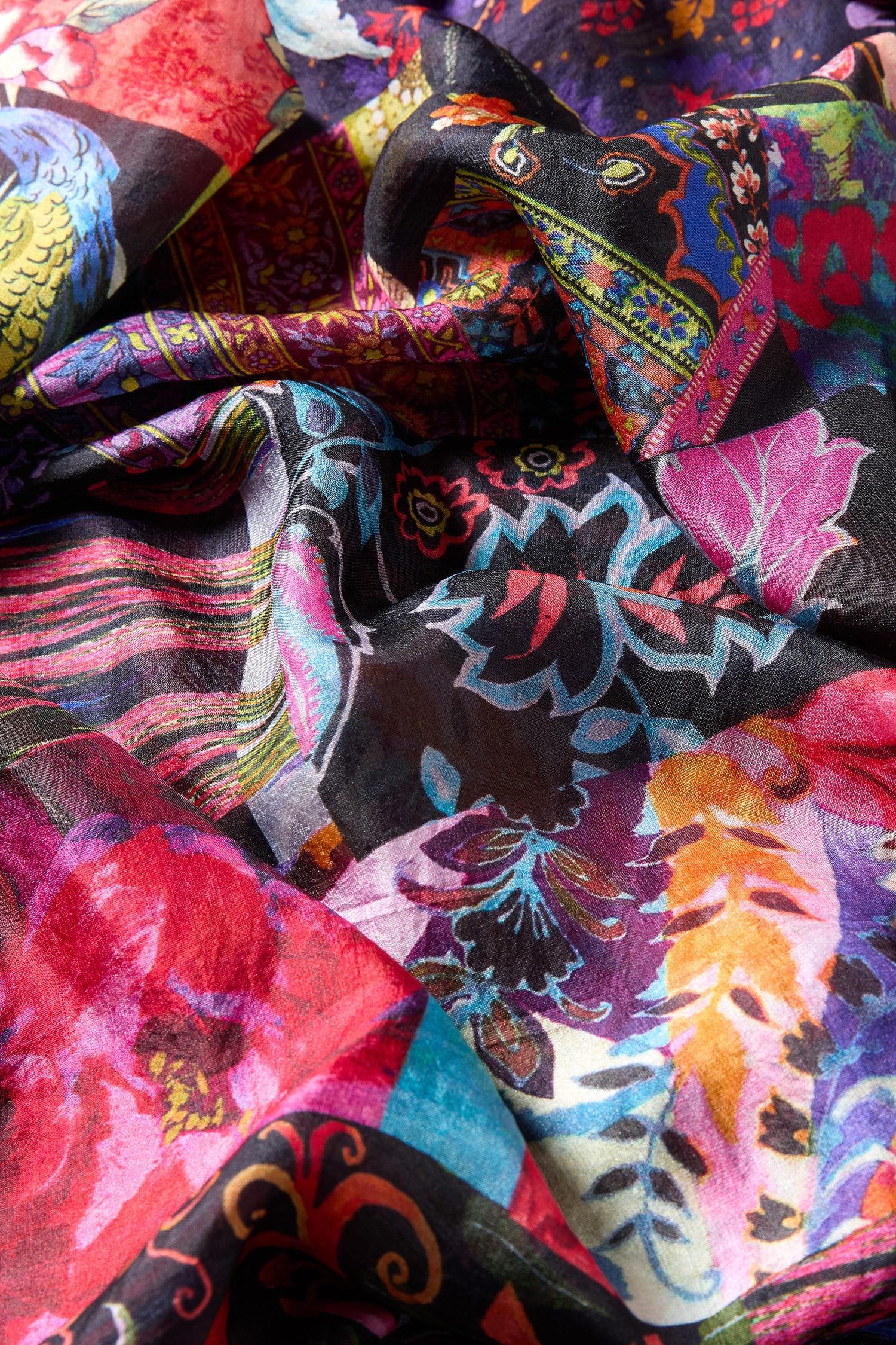 A close-up of the Sahara Winter Patchwork Scarf, showcasing vibrant floral and abstract patterns in red, pink, blue, yellow, and black hues.