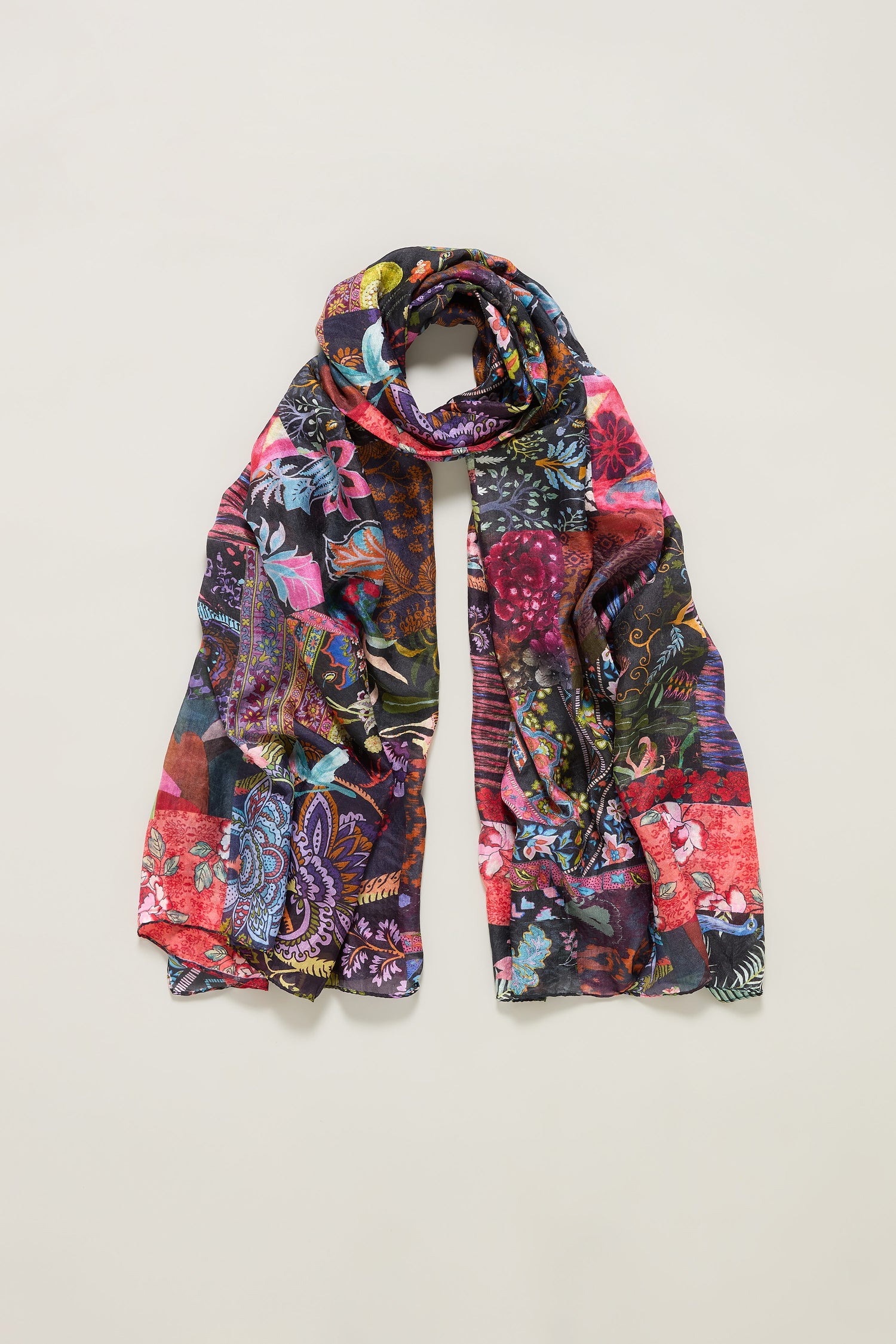 The Sahara Winter Patchwork Scarf, a long and lightweight silk accessory featuring a vibrant multicolored floral and paisley design, is displayed against a plain light background.