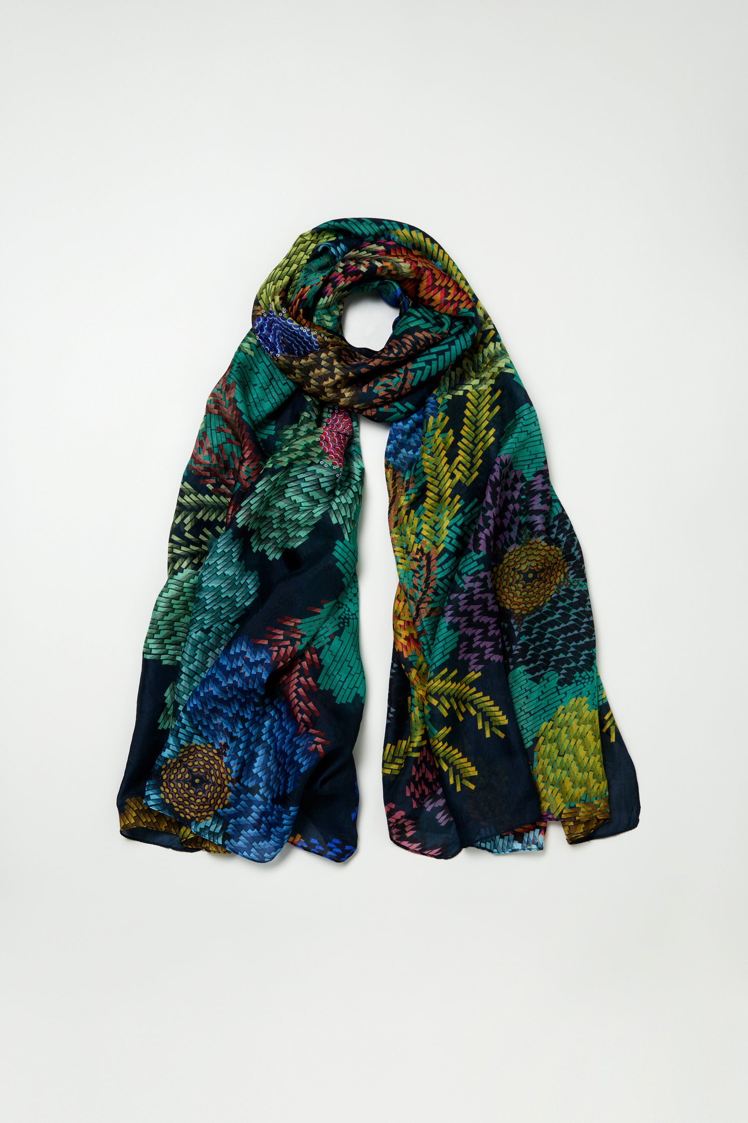 The Pixelated Petals Silk Scarf is a dark silk accessory with a colorful, pixelated floral print, shown loosely rolled and laid flat against a plain background.