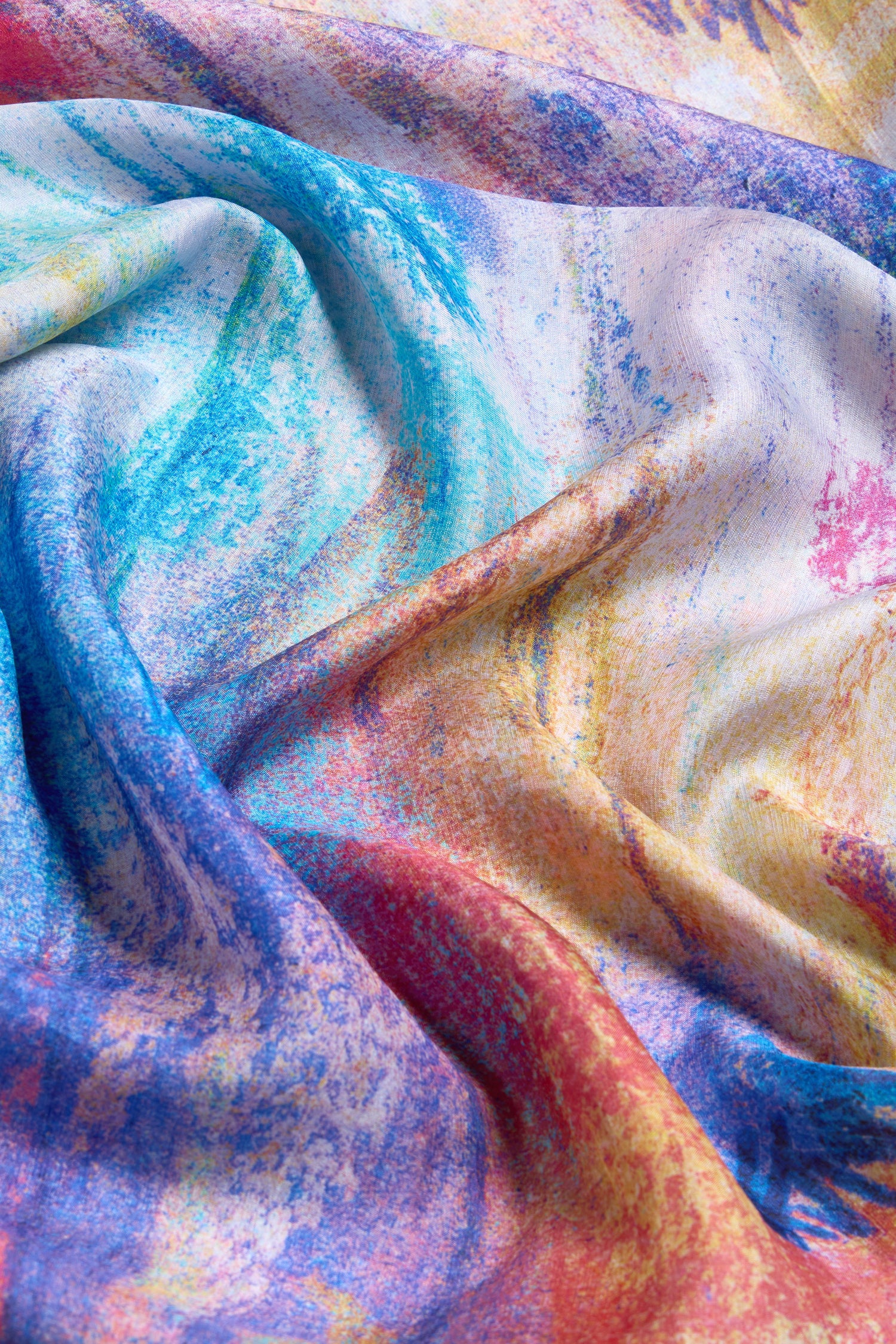 The Soft Meadow Dreams Silk Scarf features colorful, textured abstract patterns in blue, yellow, red, and purple with elegant folds—perfect as a lightweight or statement silk accessory.