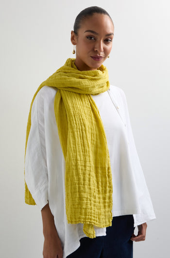 A person in a white shirt and a Crinkle Linen Scarf with a textured design stands against a plain background.