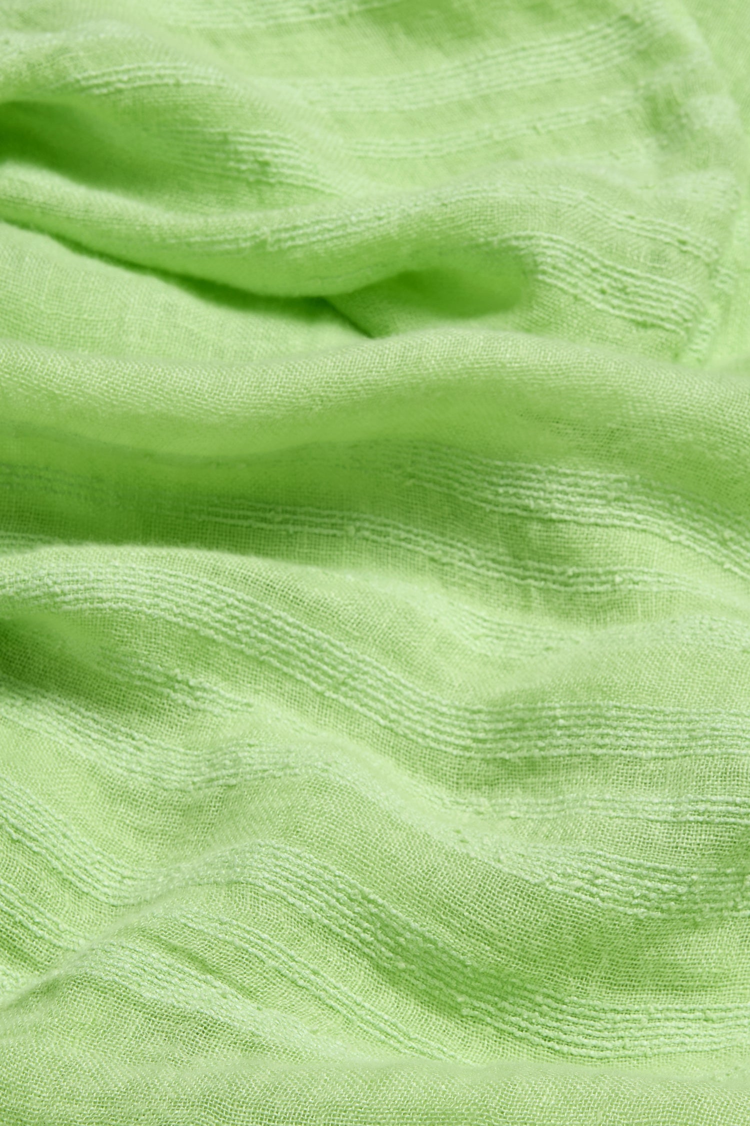 Close-up of the Crinkle Linen Scarf in light green, showcasing its textured linen, visible horizontal weave, and gentle folds—ideal for a lightweight accessory.