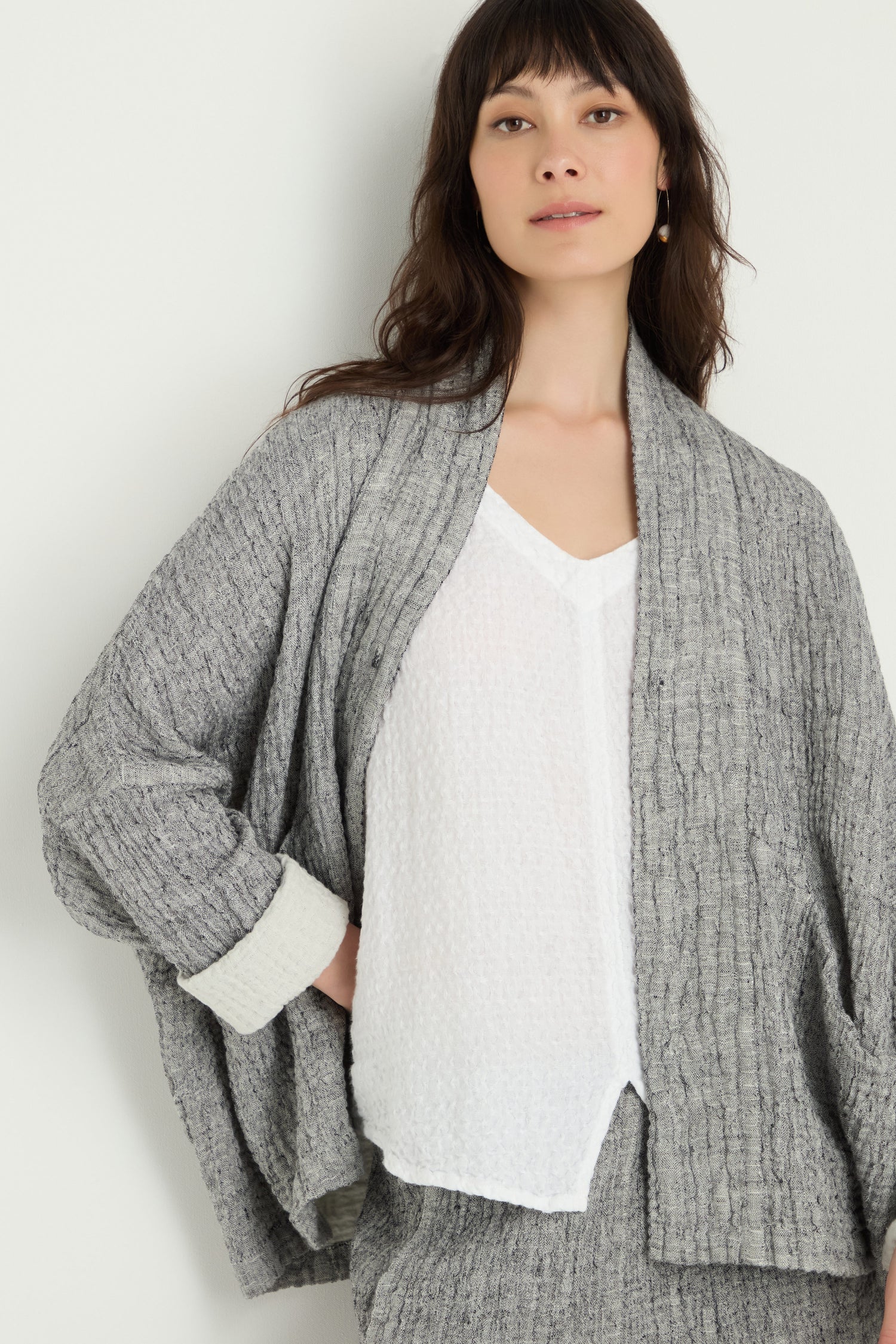 A woman models the Crinkle Double Face Linen Jacket over a white textured top, standing against a plain light background.