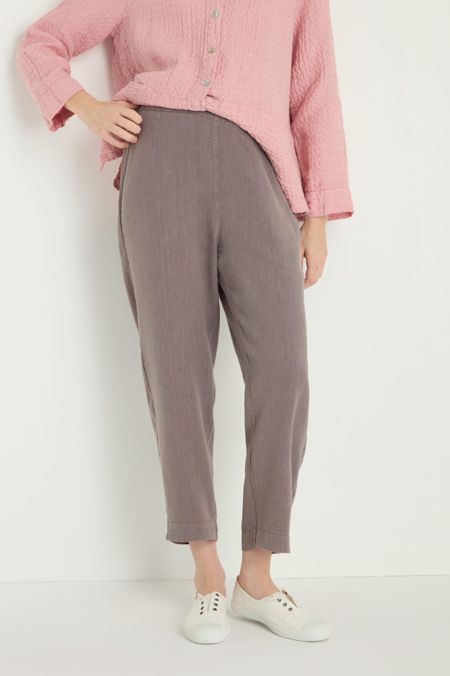 Person wearing a textured pink long-sleeve shirt, Twisted Linen Slim Trouser in gray, and white sneakers, standing against a plain white background.