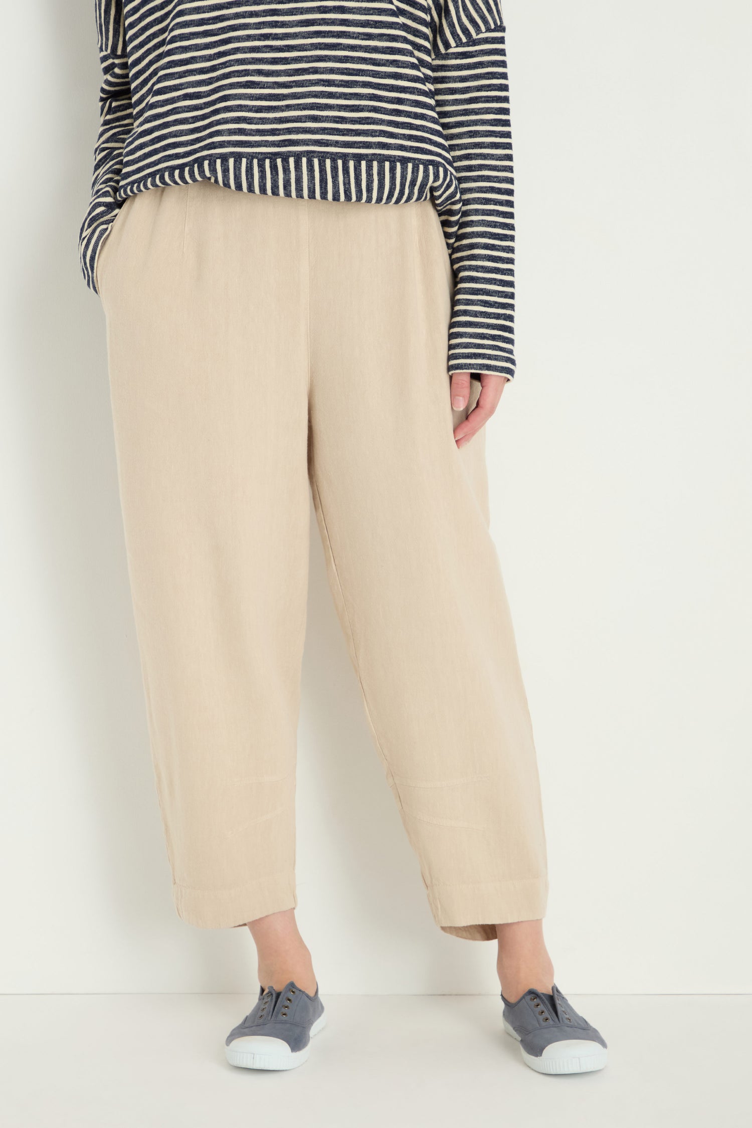 Person wears a navy and white striped long-sleeve shirt, Twisted Linen Crop Bubble Trouser for a breathable feel, and gray sneakers, standing against a plain white background.