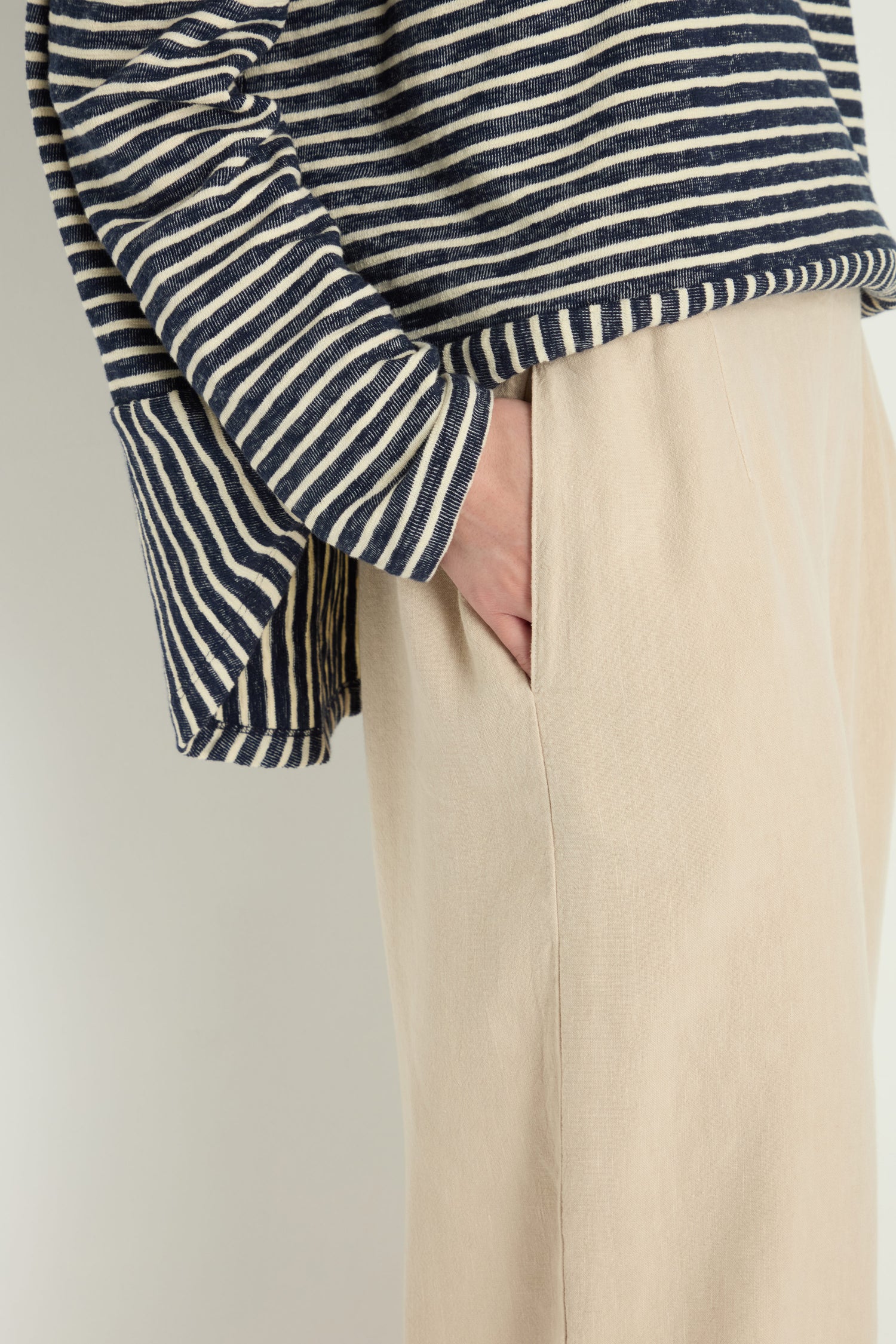Person wearing Twisted Linen Crop Bubble Trouser in beige with a navy and white striped long-sleeve top, standing with one hand in pocket; image cropped at shoulders.