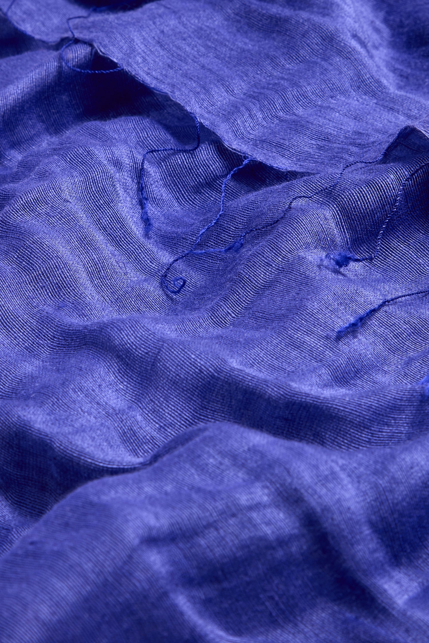 Close-up of the Soft Linen Fringe Scarf in blue, showing its textured weave, delicate folds, and fringed edges—ideal for lightweight layering.