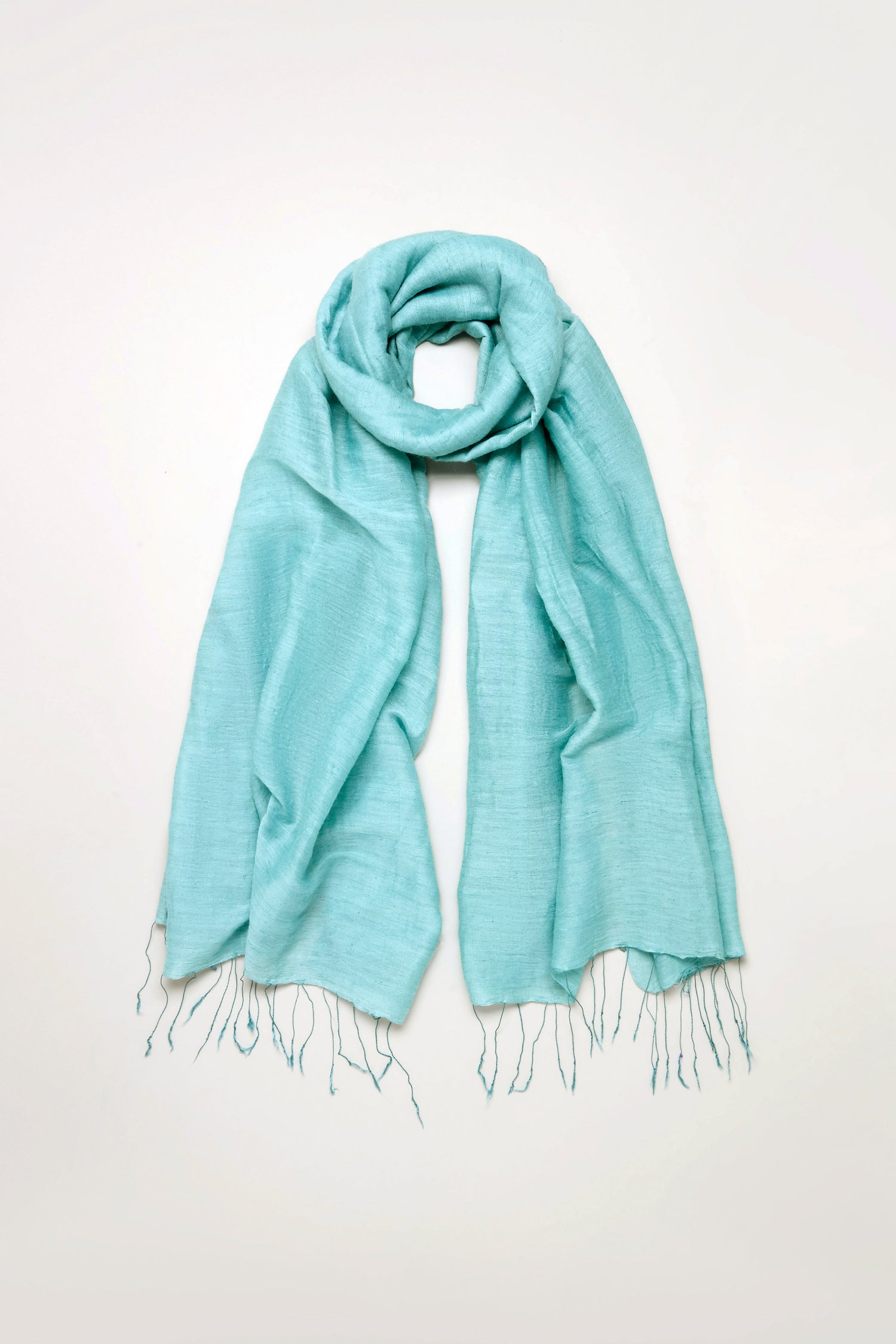 The Soft Linen Fringe Scarf in light blue, featuring fringed ends, is laid flat on a plain white background—ideal for lightweight layering.