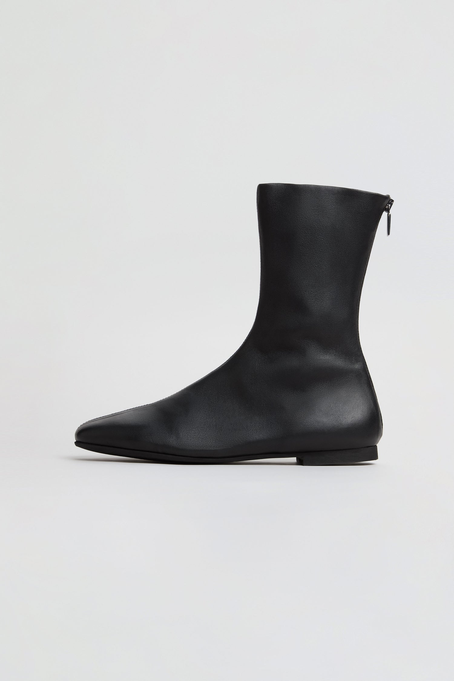A profile view of the Slim Napa Leather Stretch Boots in black, featuring soft nappa leather, a slim silhouette, a side zipper, and a flat sole, displayed on a plain light background.